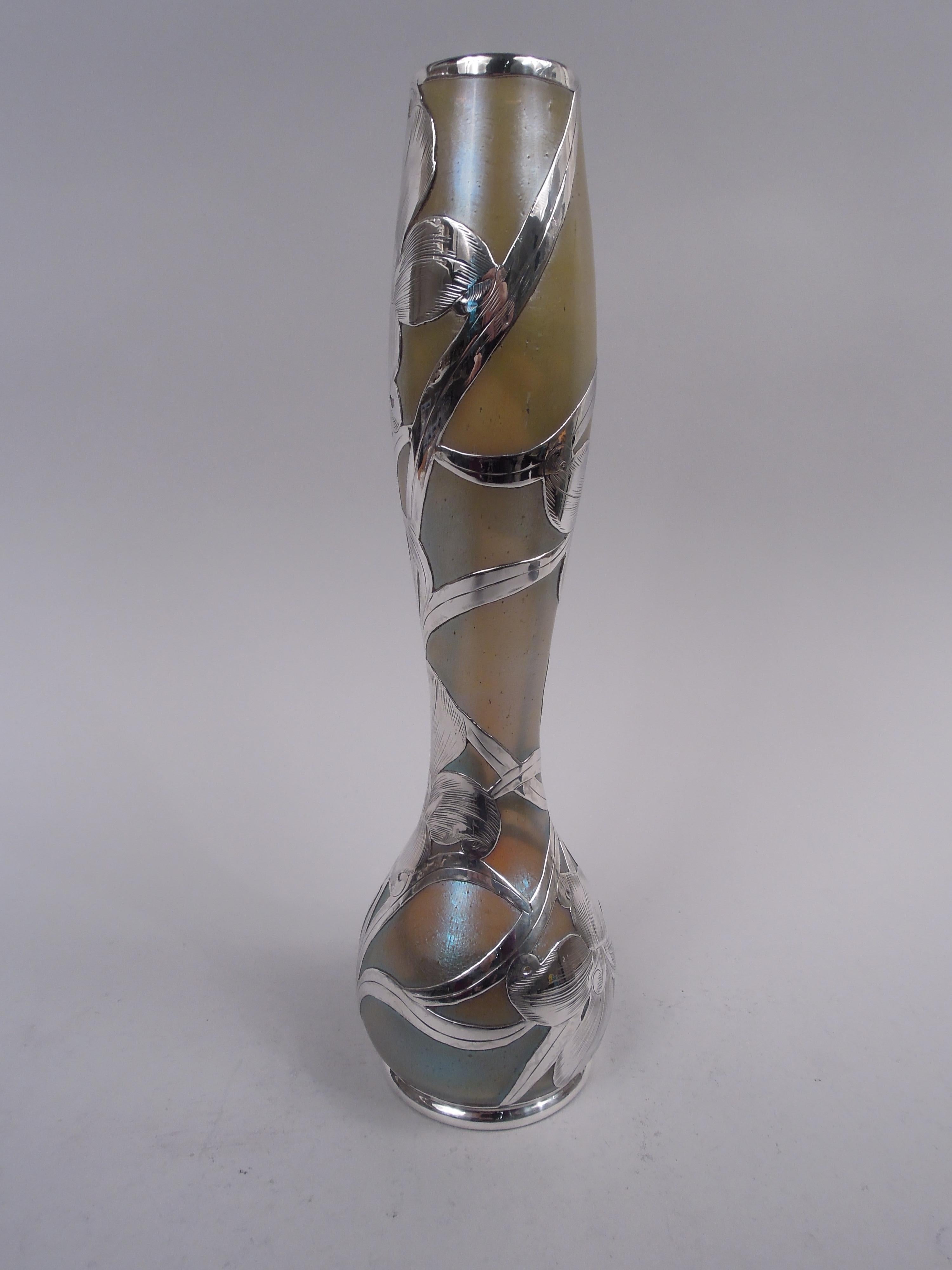 Vaso in vetro Art Nouveau di fine secolo realizzato dalla storica ditta Siecle con sovrapposizione di argento inciso. Collo alto e delicatamente a balaustro e ciotola ovoidale. Sovrapposizione di capolini sciolti e fluidi con viticci intrecciati e