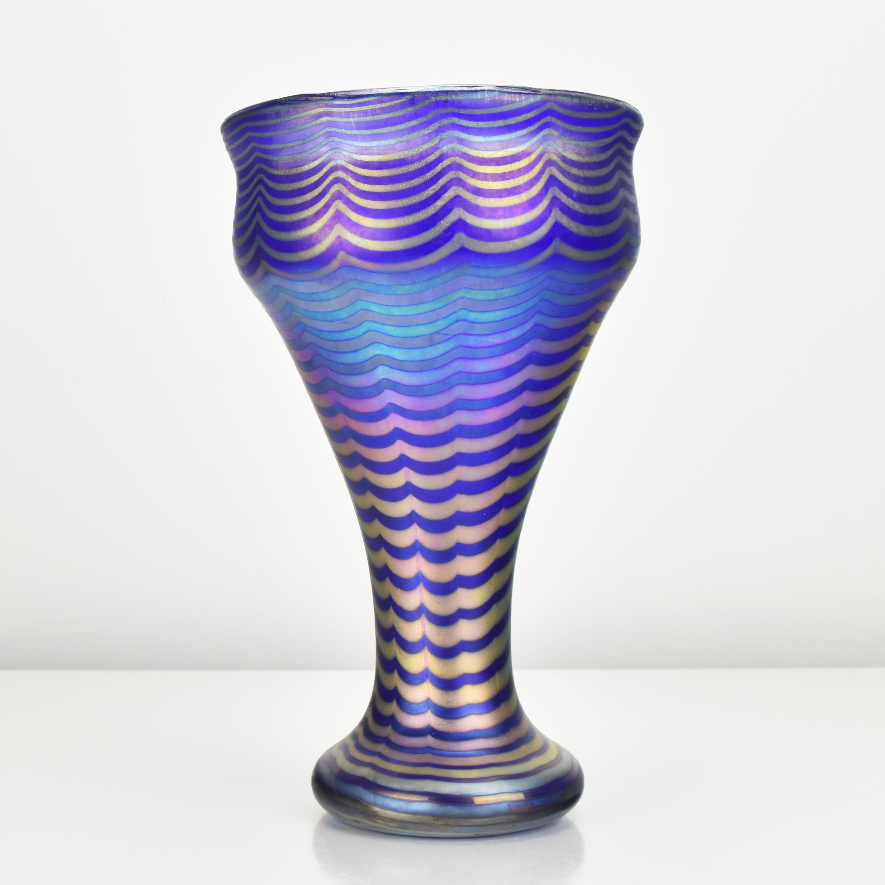 Vase ancien en verre d'art de forme calice Art Nouveau créé par la verrerie Loetz, active à la fin du 19ème et au début du 20ème siècle, ce vase représente un exemple parfait de leur maîtrise artistique.

Le fond du vase est bleu cobalt, ce qui