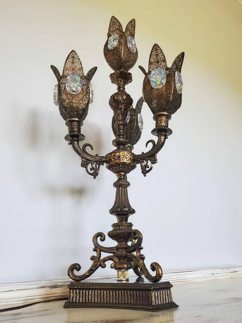 A breathtaking gilt bronze floral candelabra form four light crystal prism table lamp attributed to American mid-century Loevsky & Loevsky (L&L) New Jersey, United States. 

Having an ornate stamped and turned central standard, issuing three