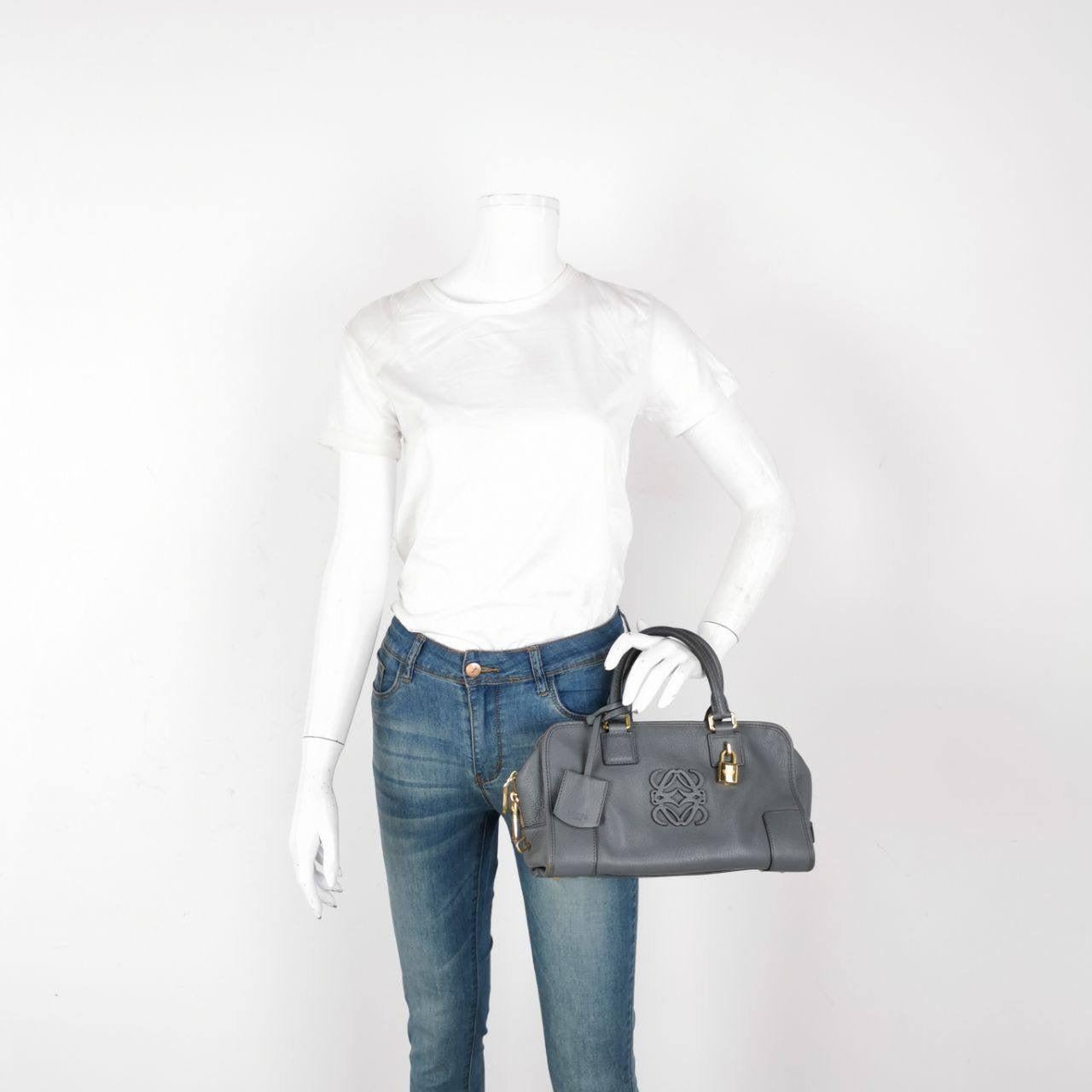 Loewe Amazona 29 en piel de cordero gris Estas son fotos profesionales del bolso real. El bolso de asa superior estilo baúl vuelve a estar de moda en 2024 gracias a los desfiles de Prada y Miumiu. El bolso Loewe Amazona es una opción elegante y
