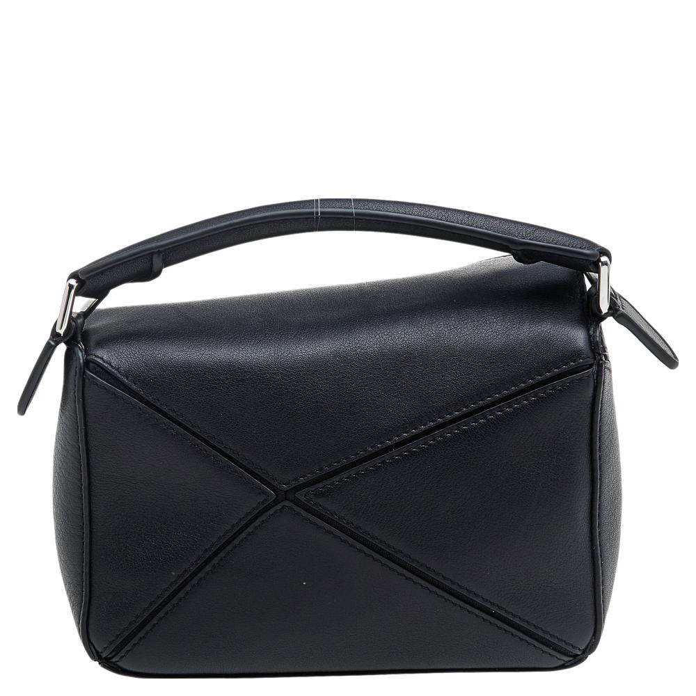 This mini Puzzle shoulder bag from the House of Loewe will suffice your handbag needs with complete elegance. This bag is designed using black leather. It showcases silver-toned hardware, a single handle drop, and a roomy fabric-lined interior. It