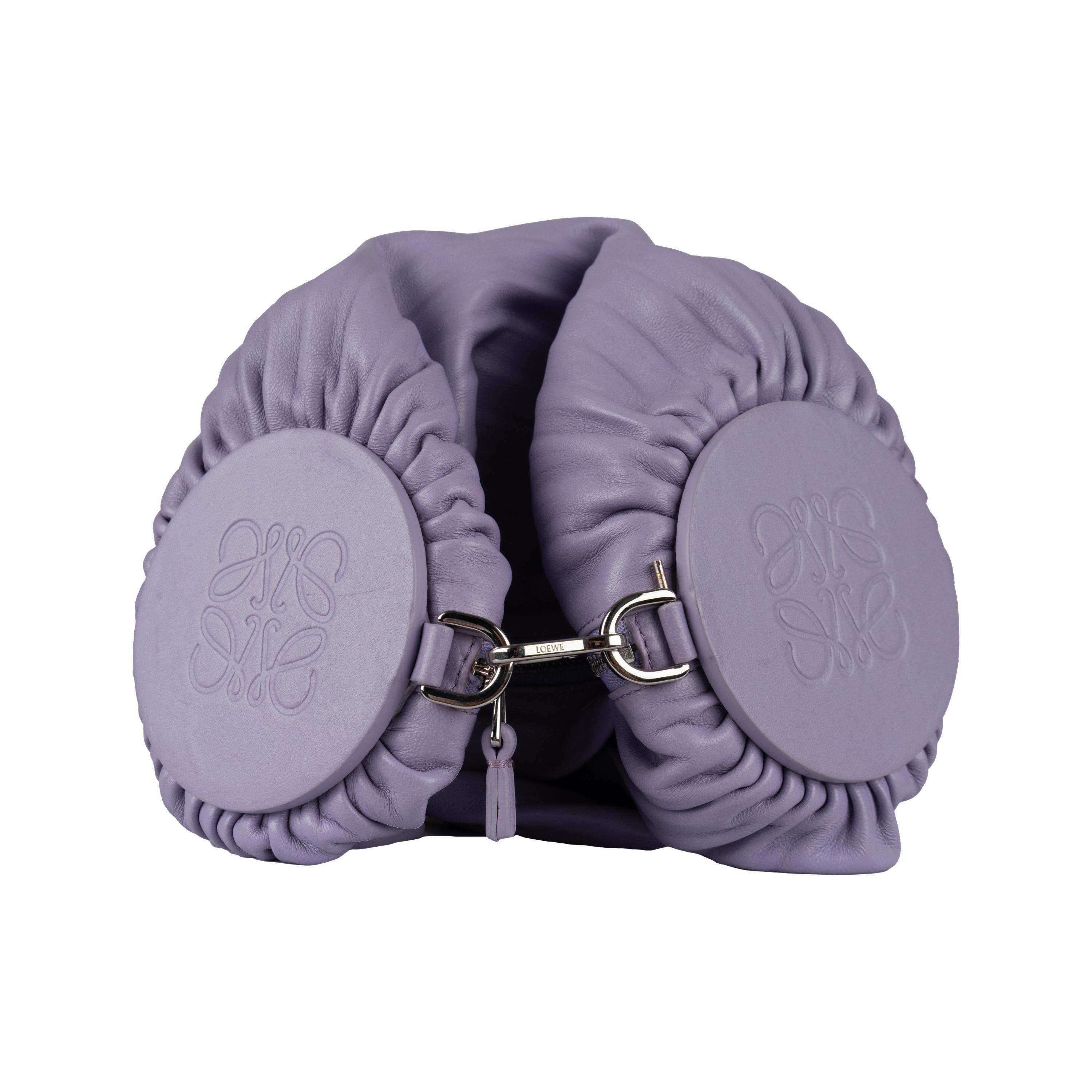 Loewe's Bracelet Pouch Bag is crafted from pleated, nappa leather in lilac color that transforms into an oversized bracelet with the detachable and adjustable strap. The zip closure and tonal pulls provide reliable security, while the engraved