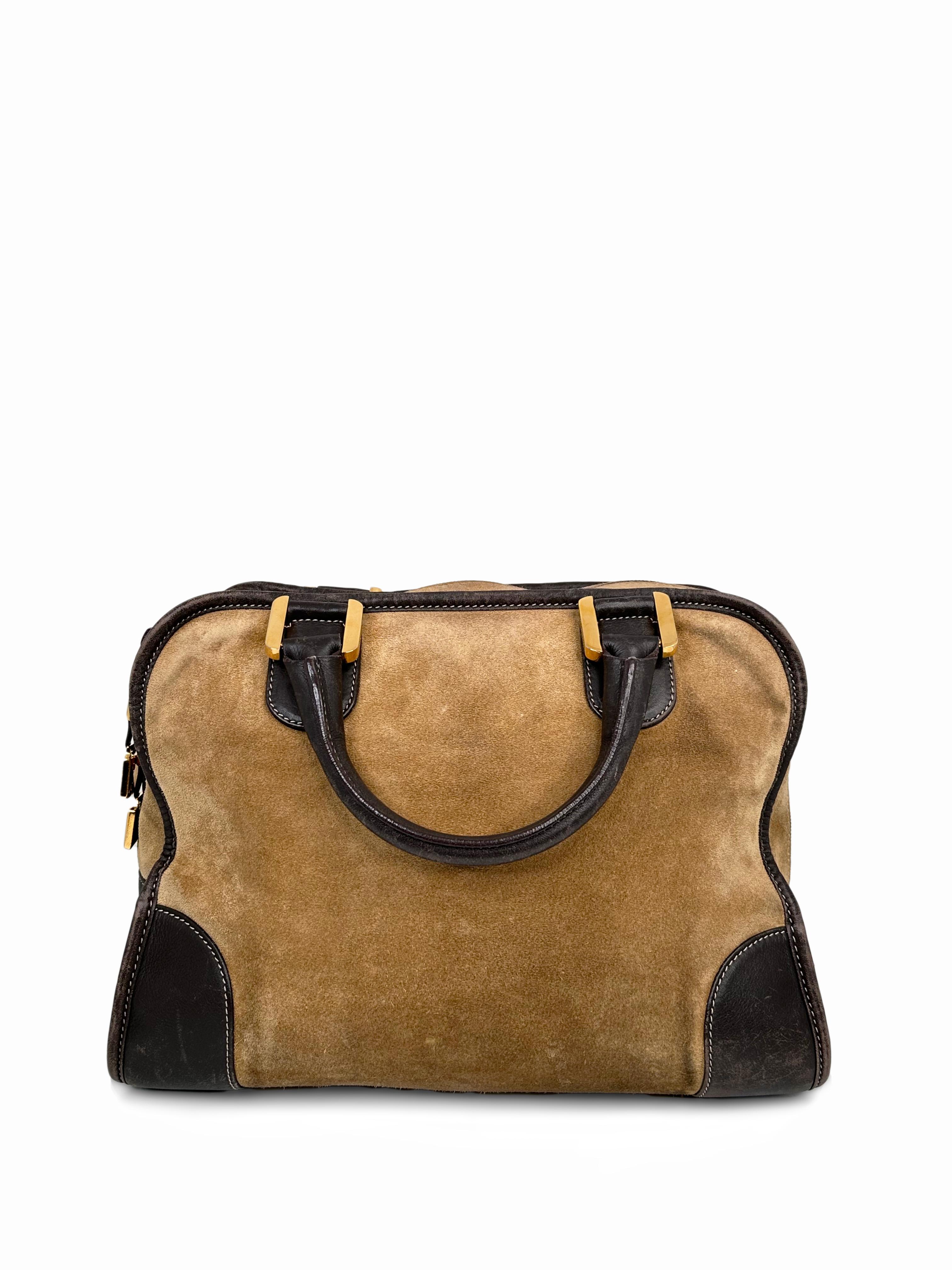 The Loewe Amazona Bag features a suede and calf leather body and rolled leather handles. The top zip closure opens to a roomy compartment featuring an interior zip pocket. It is the perfect size to carry your work and everyday essentials. This Loewe