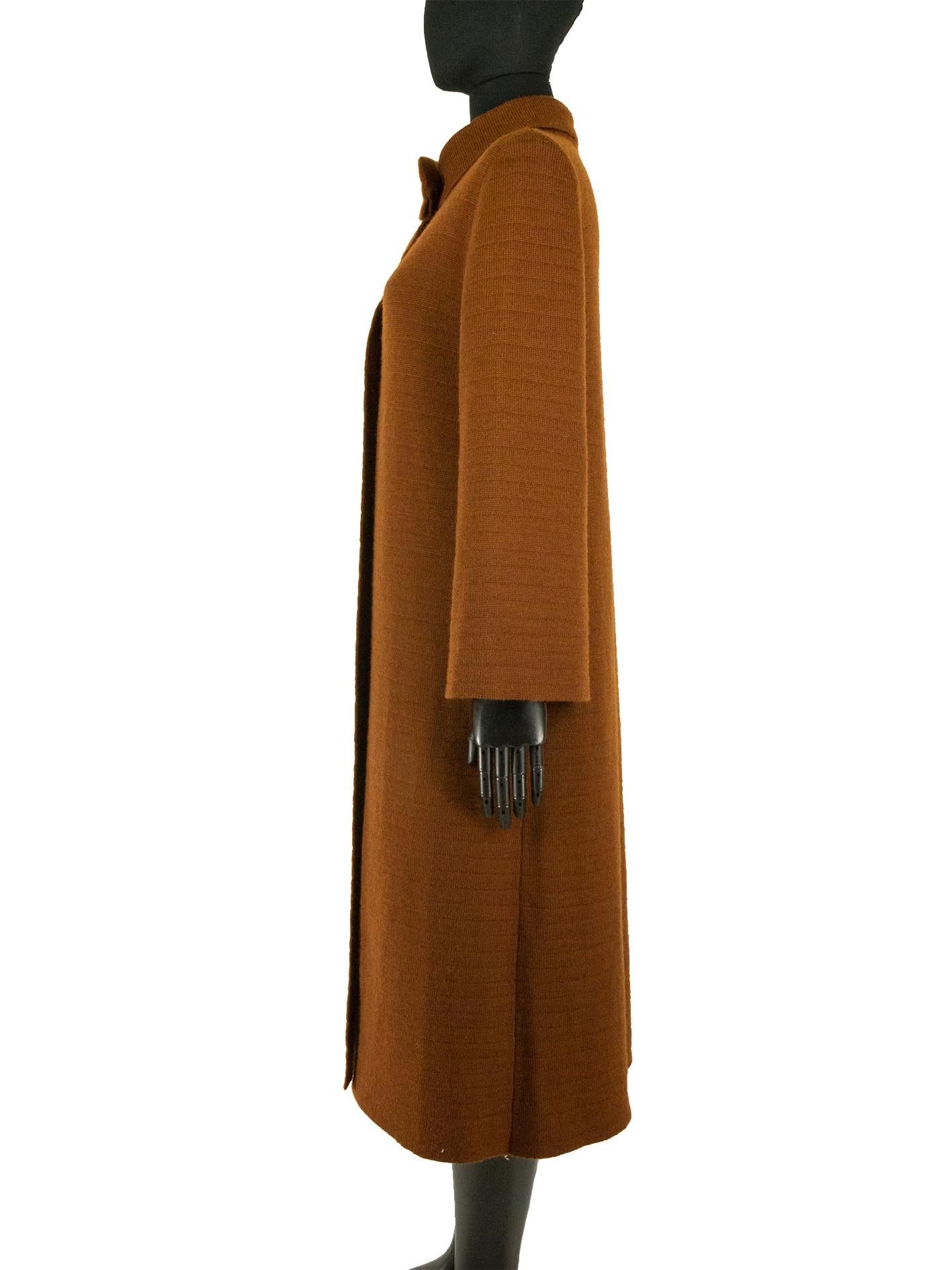 A brown Loewe coat made of virgin wool. This long wool coat features four self-covered buttons going down the main bodice of the coat. An asymmetric folded collar is a key feature of this coat, joined together with a singular hook and eye fastening.