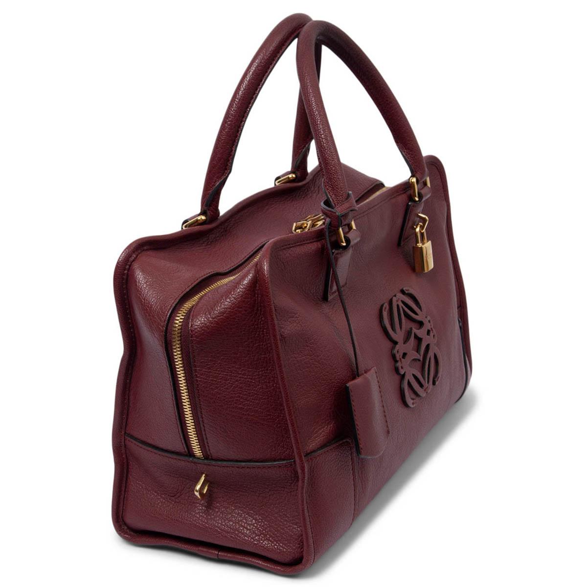 100% authentic Loewe Amazona 36 logo hand bag in burgundy leather, featuring gold-tone hardware. Open with a zipper on top and is lined in burgundy grossgrain with one zip pocket against the back and two slit pockets against the front. Comes with