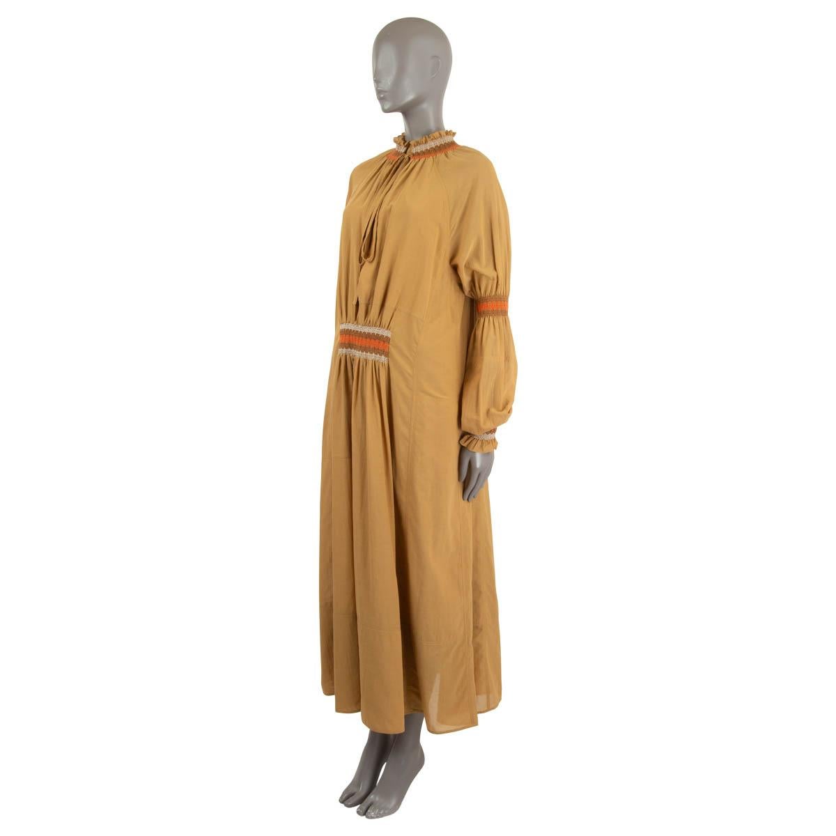 100% authentic Loewe long sleeve maxi dress in camel silk (100%) with a keyhole-neck. Features orange, white and brown  embroidered smocking on the neck arm and front. Closes on the front with string. Lined in silk (100%). Has been worn and is in