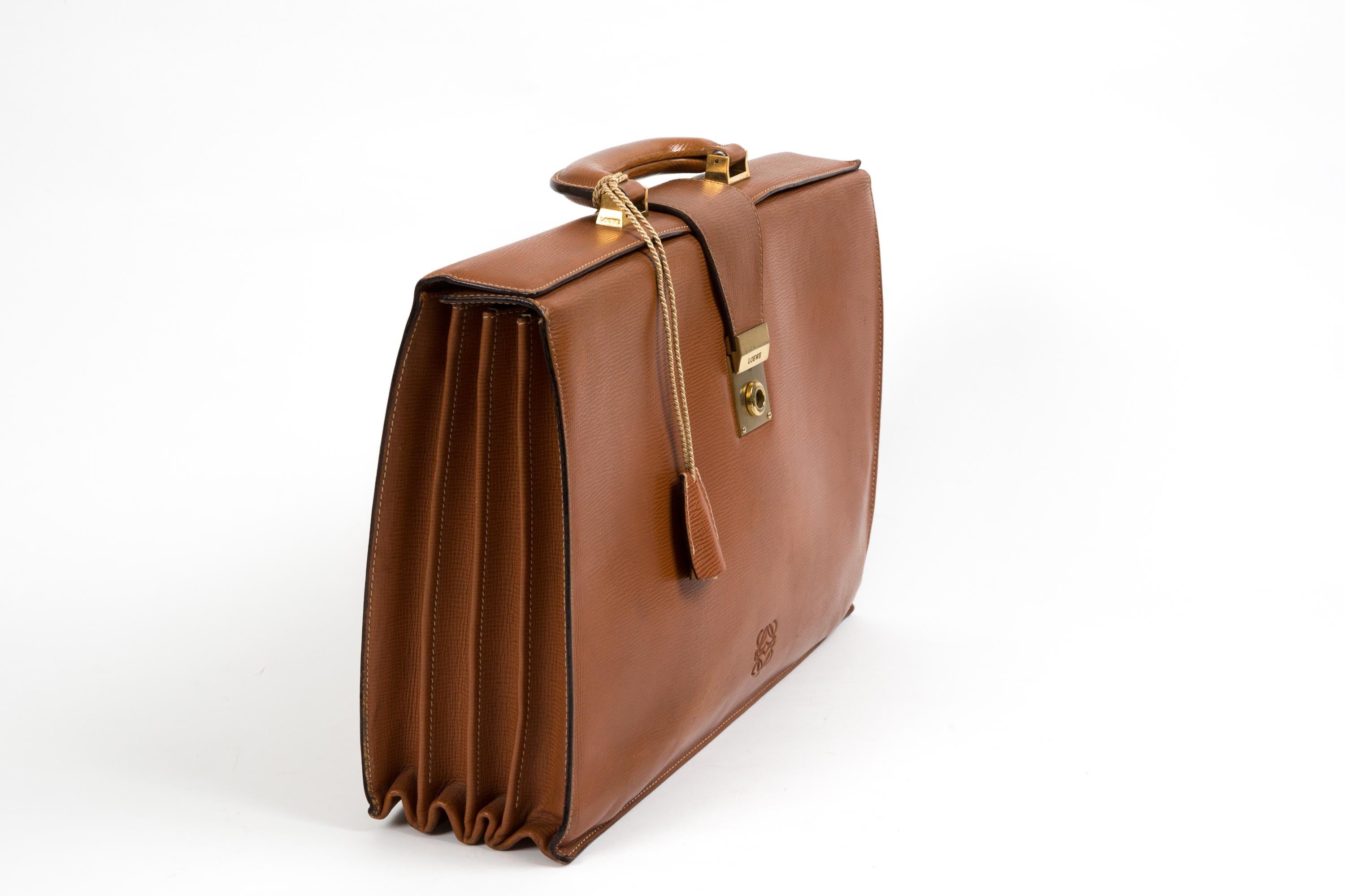 Porte-documents en cuir texturé Loewe Camel avec  une poignée supérieure, une ouverture par le haut, des compartiments intérieurs, une quincaillerie dorée, un jeu de clés et un logo.
Circa 1980   
En bon état vintage. Fabriqué en Espagne.
Longueur à
