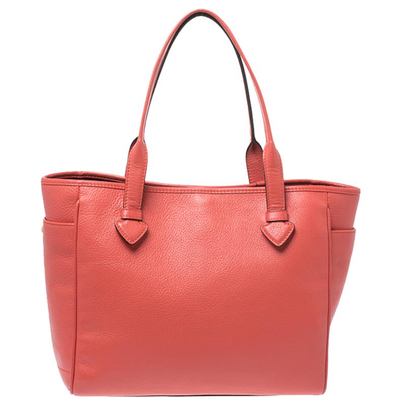 Meant for carrying all your essentials with ease is this tote by Loewe. Crafted from leather, it comes in a stunning shade of coral orange. The bag has dual handles, two exterior side pockets, a brand logo, a nylon-lined interior with a zip pocket
