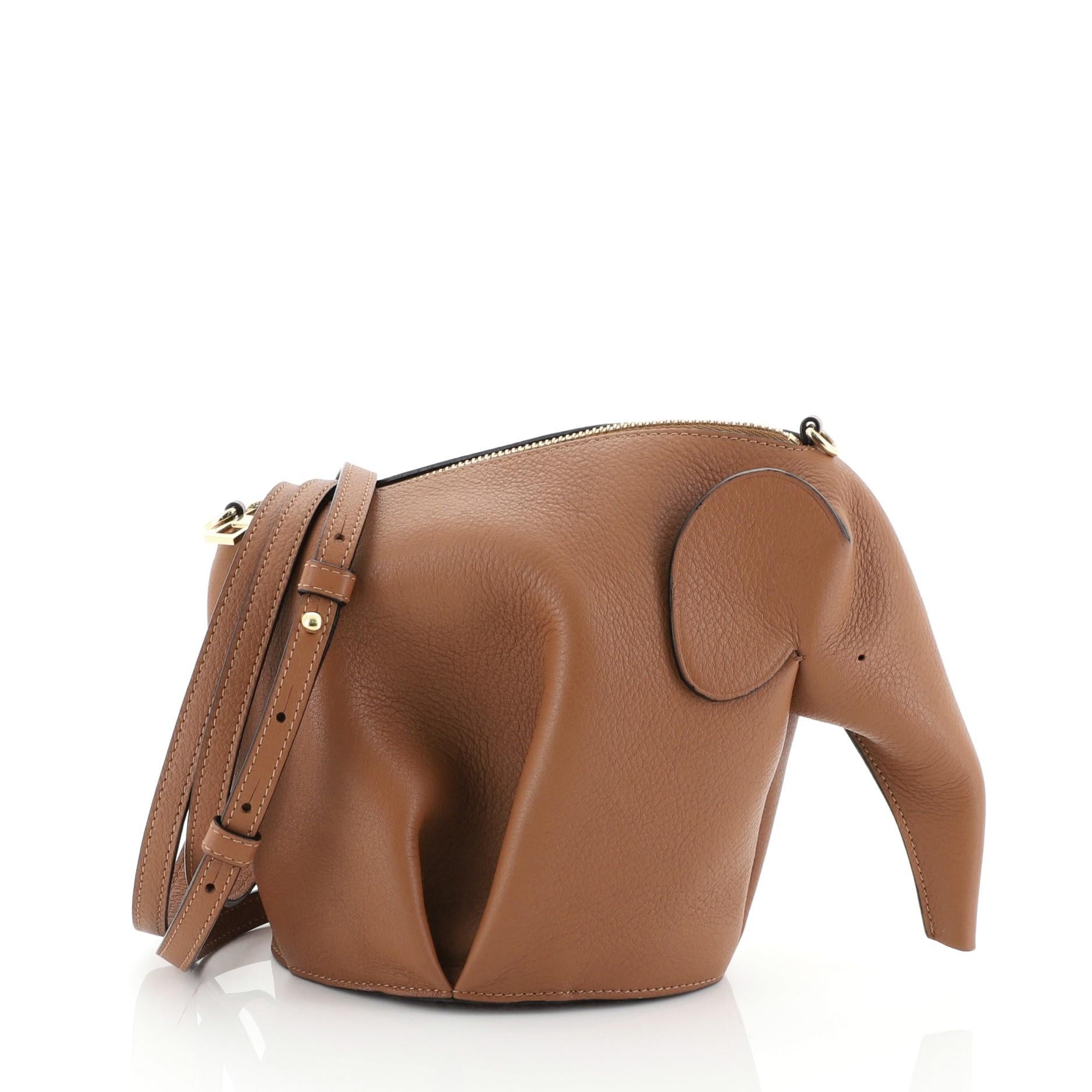 This Loewe Elephant Crossbody Bag Leather Mini, crafted in brown leather, features an adjustable crossbody strap, an elephant silhouette complete with a long trunk and dot-perforated 
