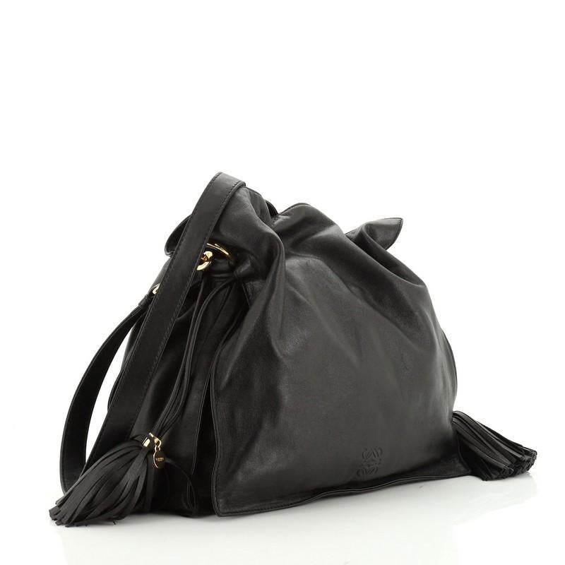 This Loewe Flamenco Bag Leather Medium, crafted in black leather, features dual leather strap, and gold-tone hardware. Its drawstring closure opens to a purple fabric interior divided into three compartments with side zip pocket. 

Estimated Retail