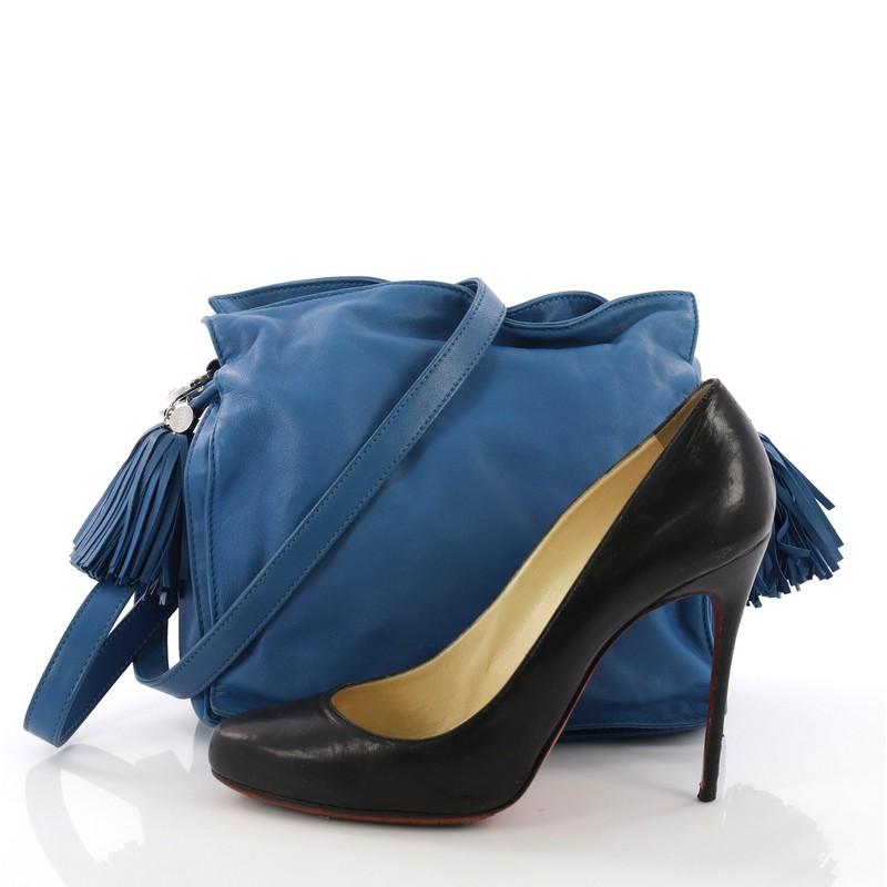 This Loewe Flamenco Bag Leather Small, crafted in blue leather, features leather shoulder strap, drawstring top with oversized tassels, and silver-tone hardware. Its drawstring closure opens to a black fabric interior with side zip pocket. **Note: