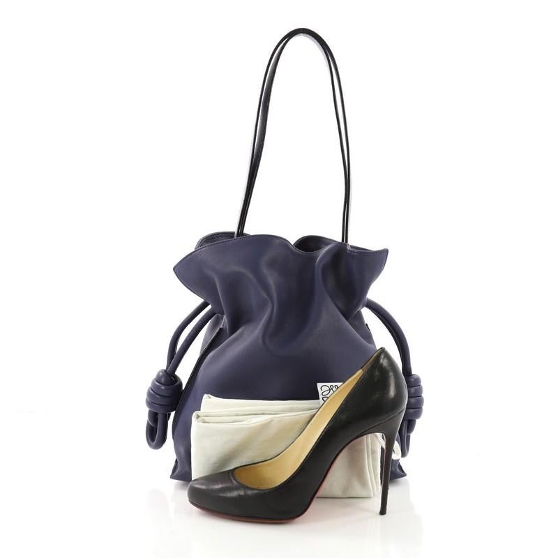 This Loewe Flamenco Knot Bag Leather Small, crafted in blue leather, features a leather shoulder strap, drawstring top with oversized knots, and silver-tone hardware. Its drawstring closure opens to an off-white fabric interior with side zip pocket.