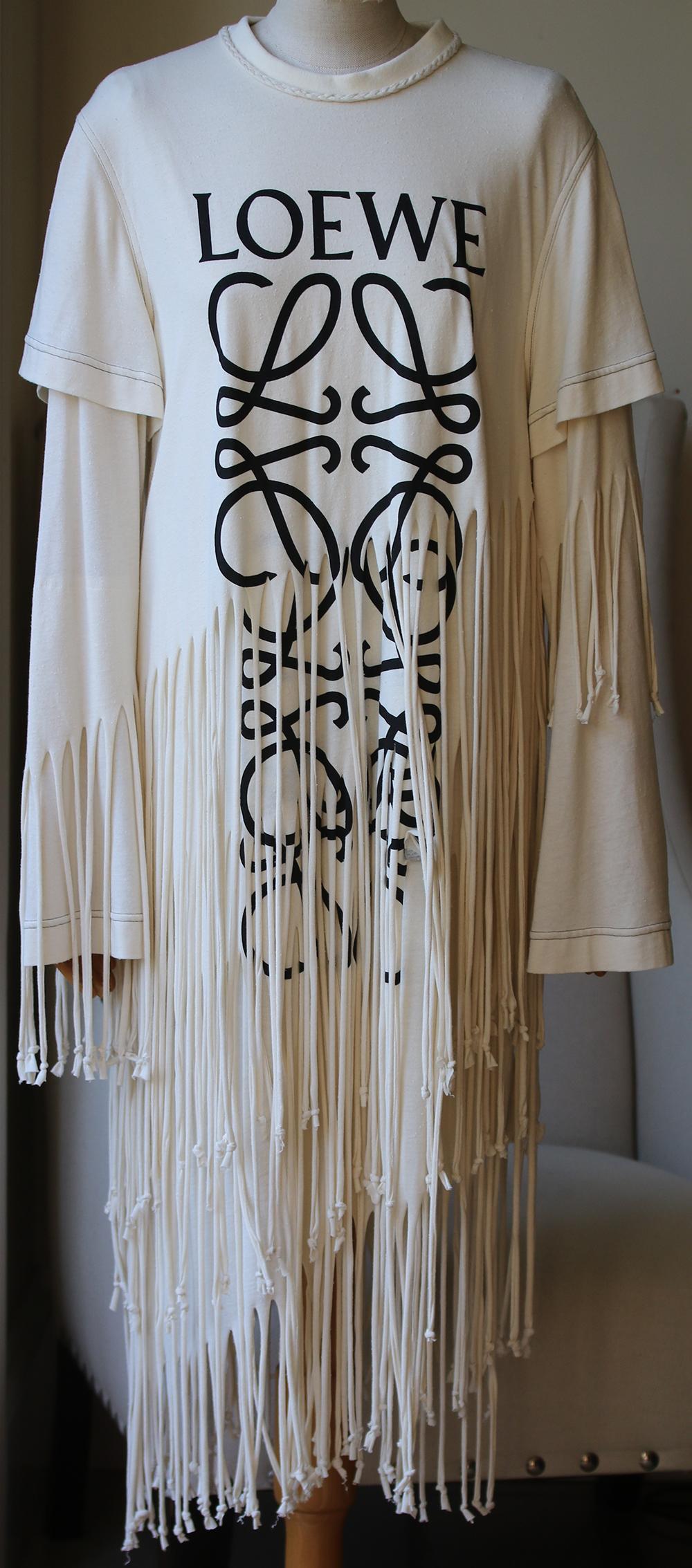 This Loewe Fringe T-Shirt Dress features a layered style with long & short sleeves, and the Loewe logo. Knotted fringe. Braided crewneck. Unlined. 50% Silk, 50% cotton. Colour: beige. Pull over. Made in Italy.

Size: Medium (UK 10, US 6, FR 38, IT
