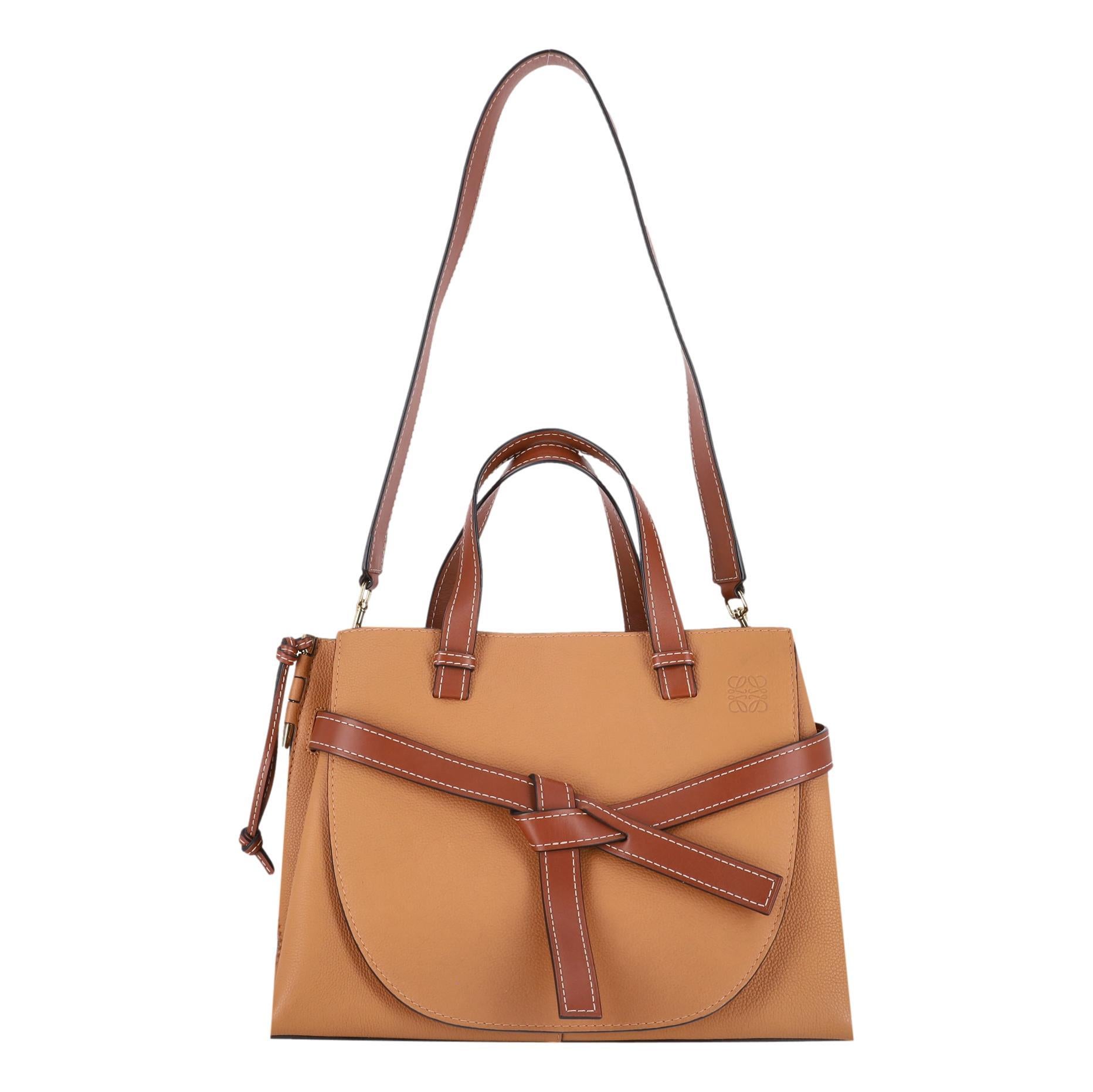 Bolso Tote Mediano Loewe Gate Piel de Becerro

Bolso marrón caramelo diseñado con detalles de nudos de cuero marrón oscuro en el centro.

Detallada con el logotipo de Loewe repujado en la esquina superior derecha, y doble asa superior con bandolera