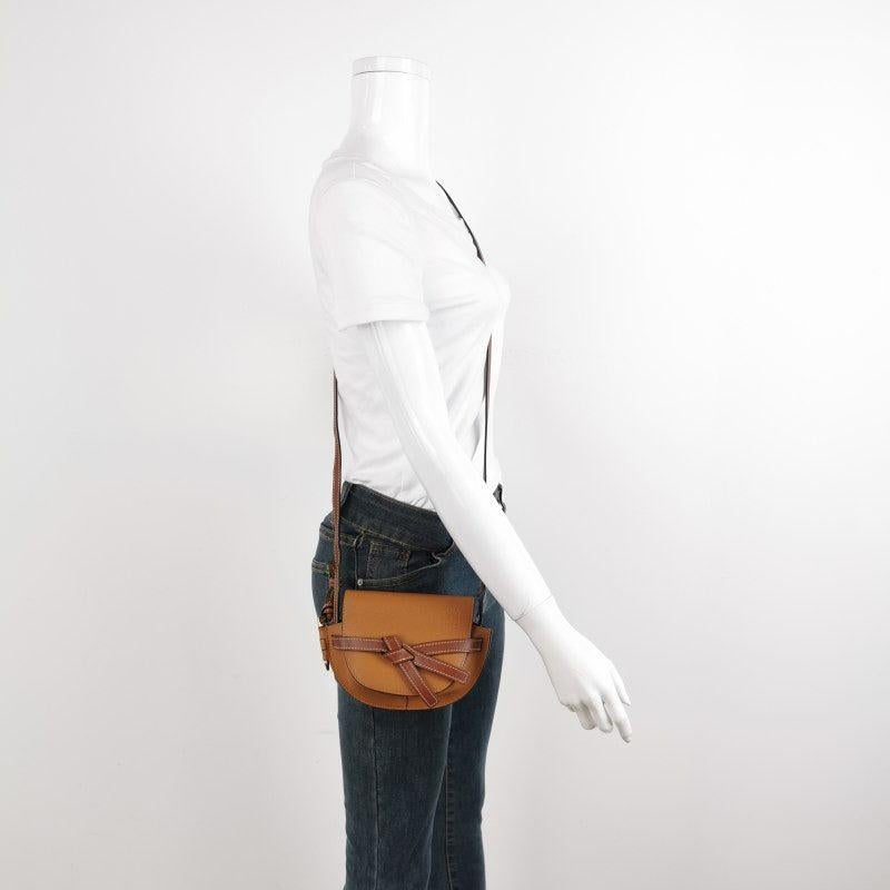 Loewe Gate Mini Tan Brown Crossbody Bag
These are professional photos of the actual bag.
  
  The Loewe Gate Mini Tan Brown Crossbody Bag exemplifies the brand's superior leather techniques, featuring a saddle-stitched knotted strap and unique