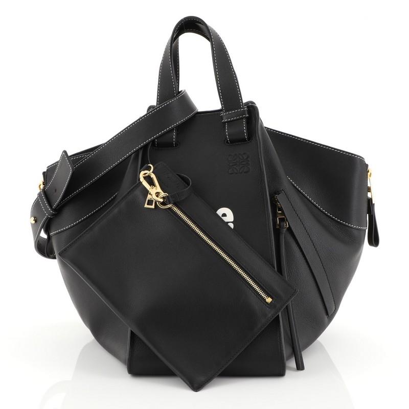 This Loewe Hammock Bag Leather Medium, crafted in black leather, features dual top flat handles, exterior zip pocket, side zip gussets, and gold-tone hardware. It opens to a black fabric interior. 

Estimated Retail Price: $2,325
Condition: Great.