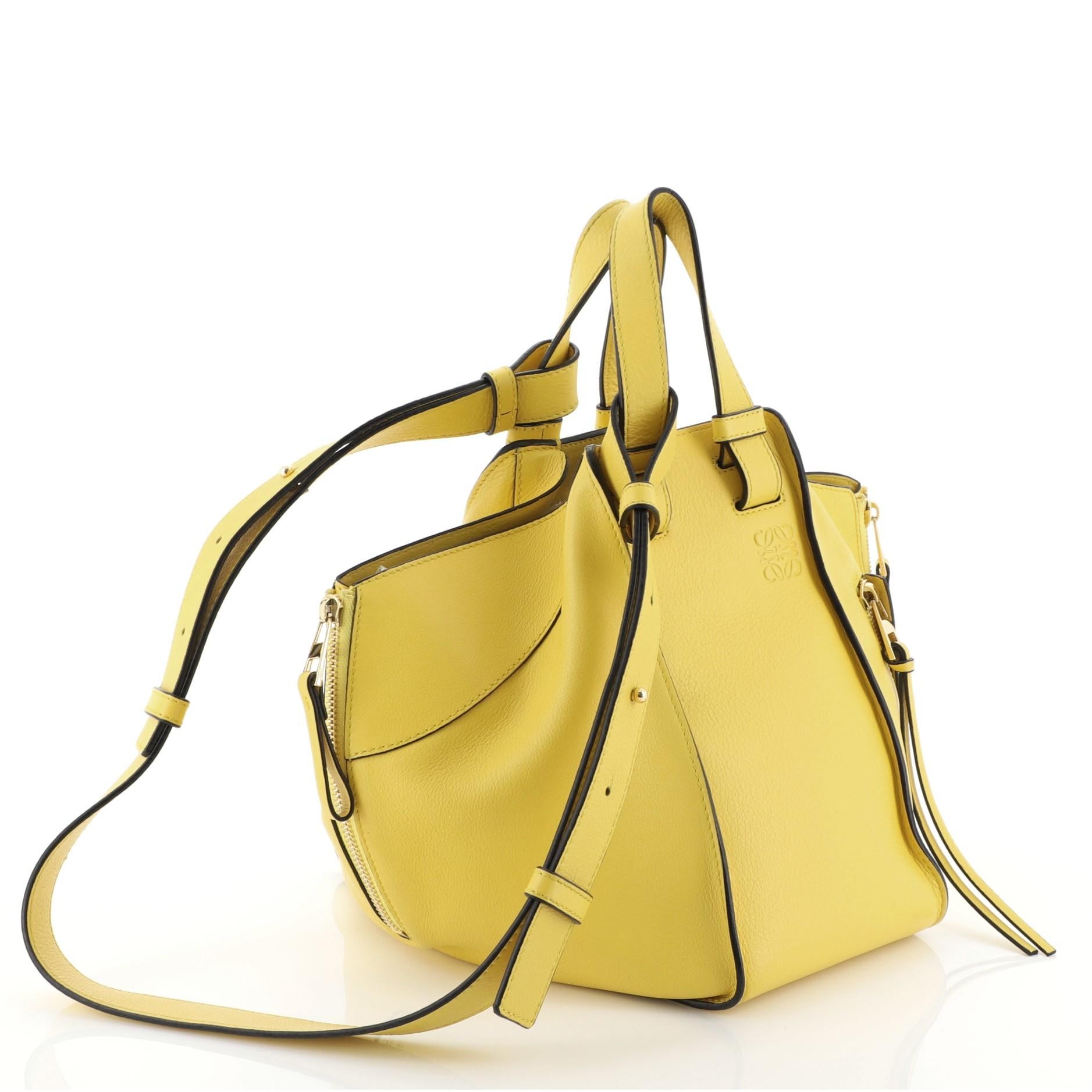 This Loewe Hammock Bag Leather Small, crafted in yellow leather, features dual top flat handles, exterior zip pocket, side zip gussets, and gold-tone hardware. It opens to a black fabric interior with slip pocket. 

Estimated Retail Price: