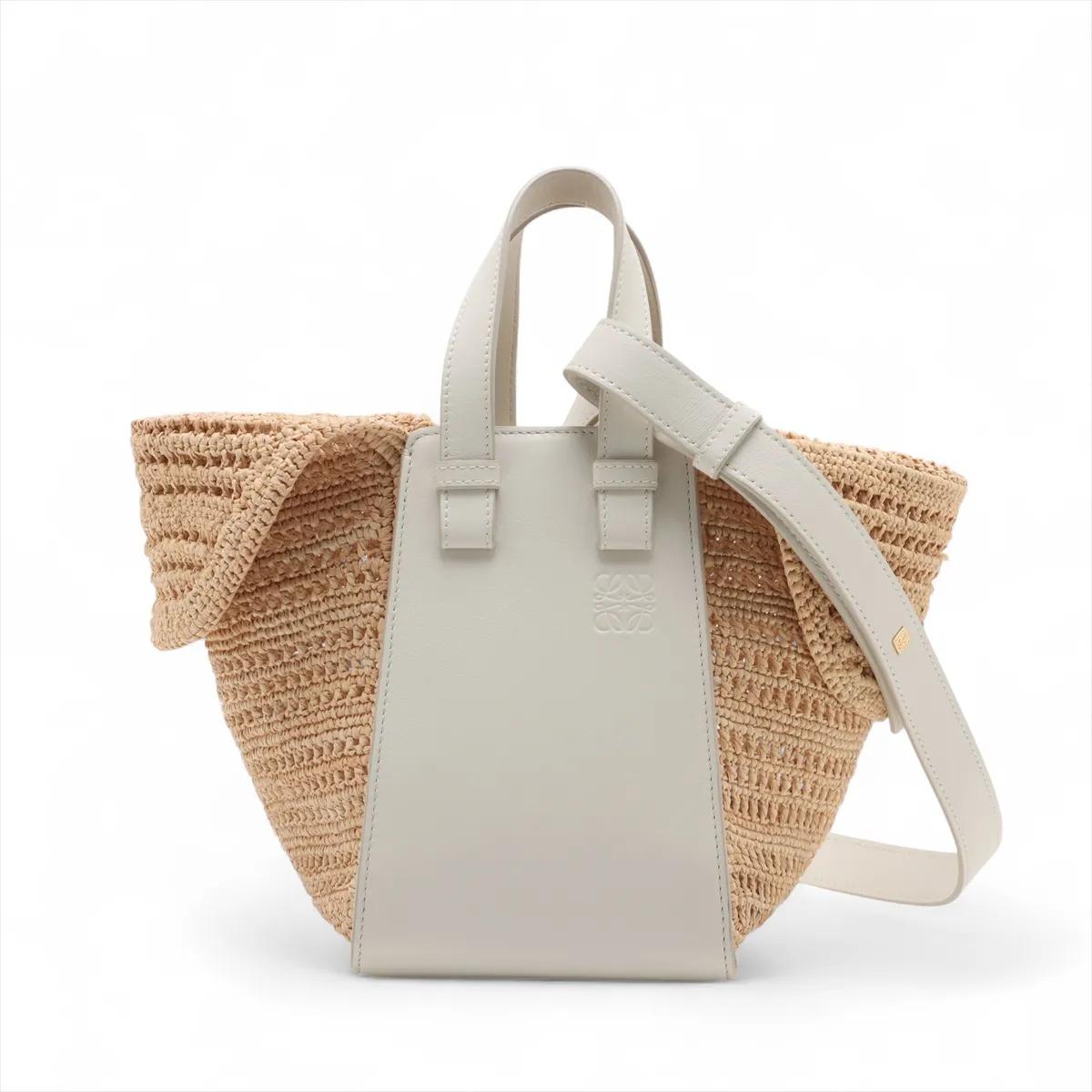 La borsa a tracolla Loewe Hammock Compact in rafia e pelle nei colori bianco e beige è una borsa a due vie splendidamente realizzata che combina la rafia naturale con raffinati accenti in pelle. Disegnata con la tipica silhouette ad amaca di Loewe,