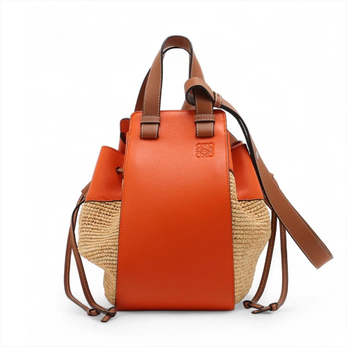 La borsa a tracolla Loewe Hammock Drawstring Medium in pelle di paglia in marrone e arancione è un design versatile che unisce la creatività moderna a un'artigianalità senza tempo. Realizzata in paglia intrecciata con accenti in pelle liscia,
