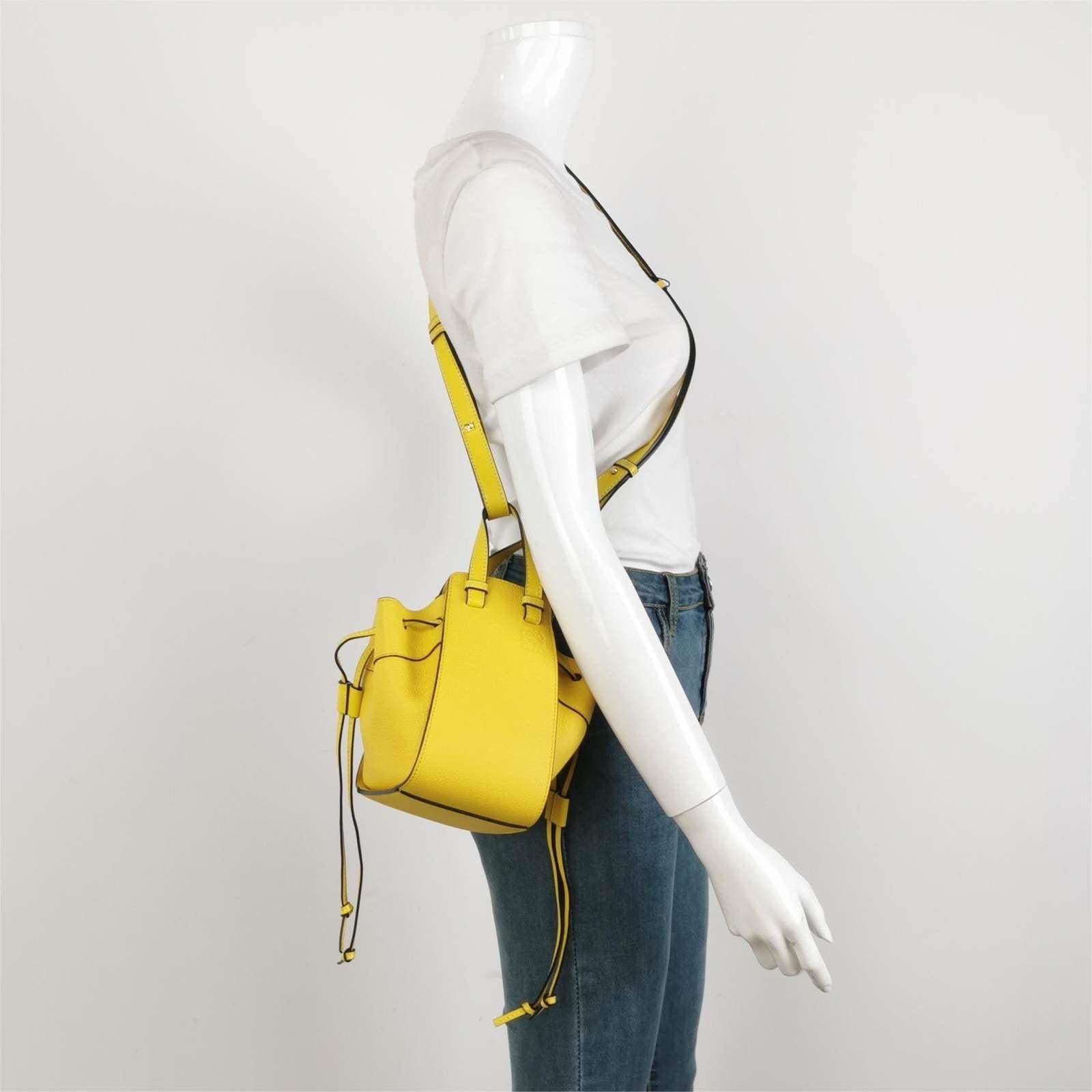 Loewe Hammock Mini Yellow Calfskin Leather Top Handle Crossbody Bag These are professional photos of the actual bag offered by Luxbags. With a versatile and attention-grabbing design, LOEWE's Hammock Bag boasts a shape that serves multiple purposes.