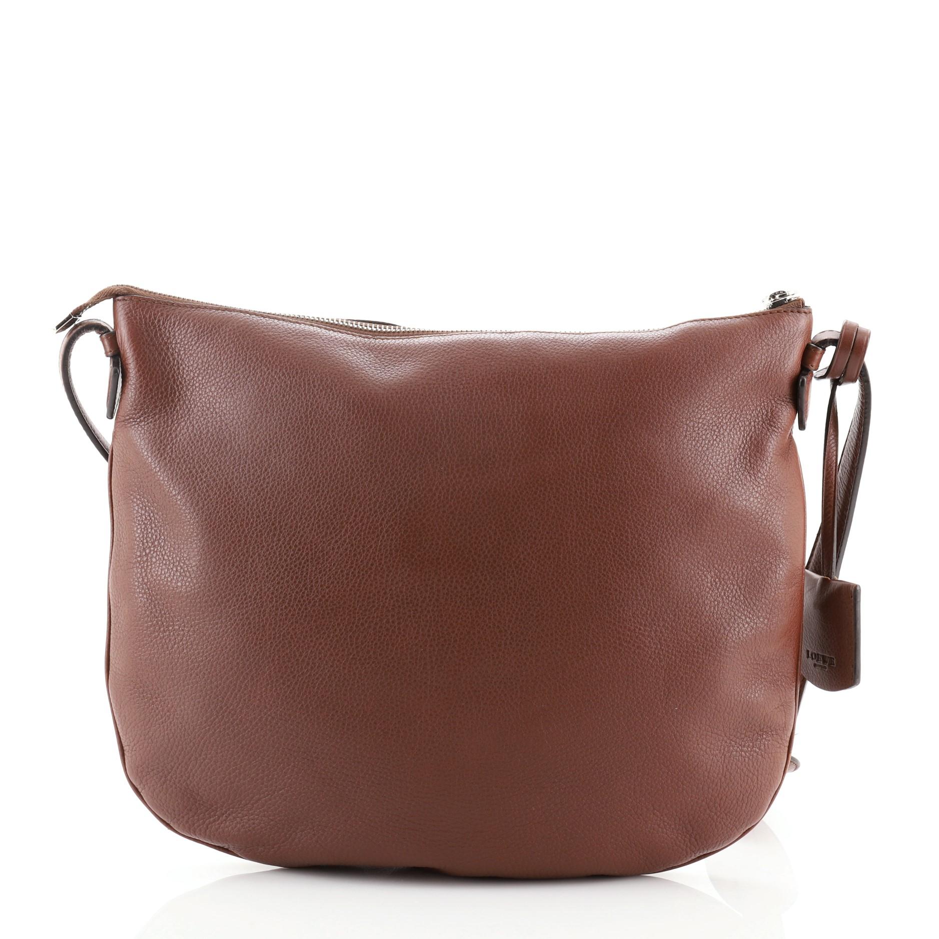 Loewe Heritage Messenger Leather
Brown

Condition Details: Wear and scuffs on exterior and exterior edges, small mark on front. Cracking and peeling on strap wax edges near base, scratches on hardware.

51945MSC

Height 11.5