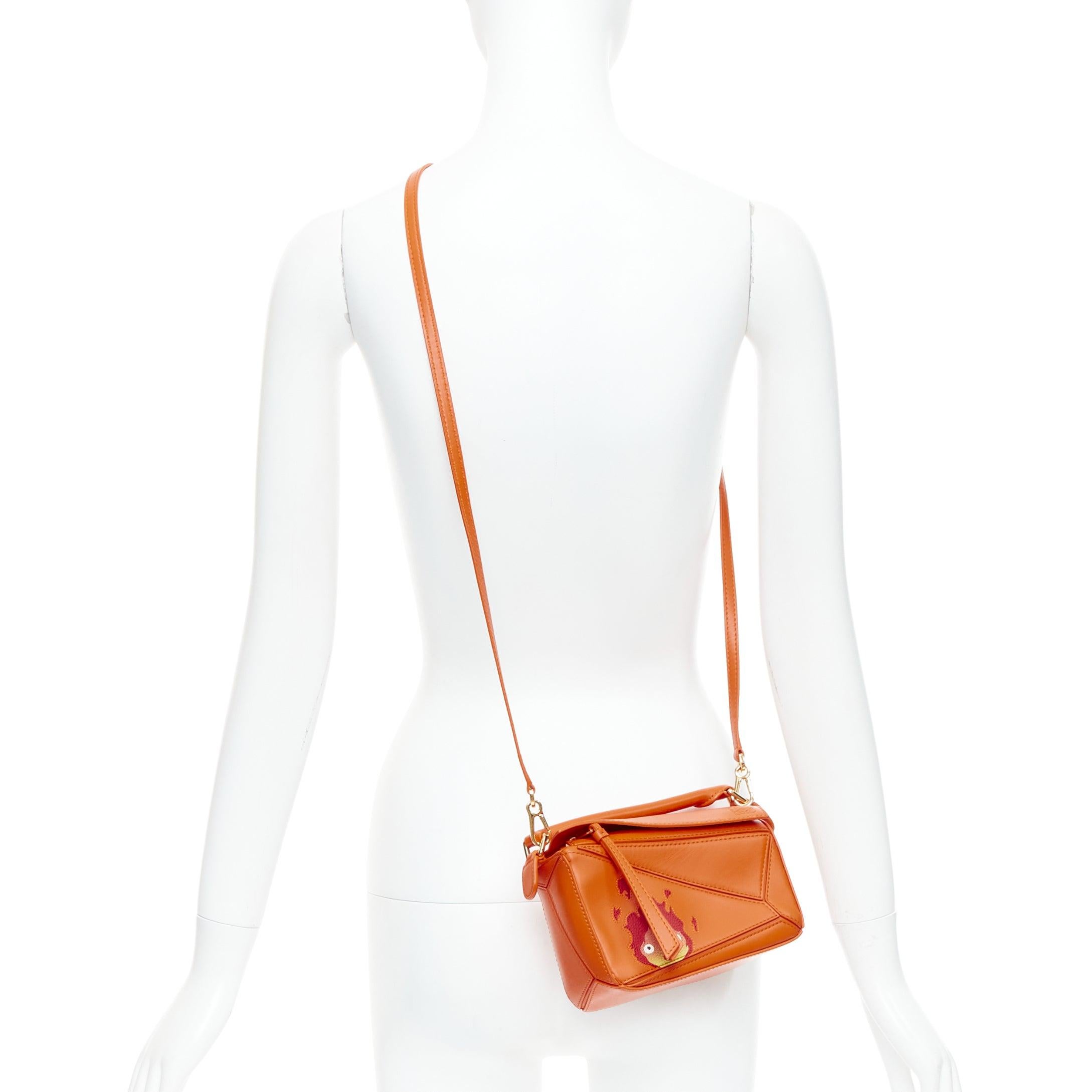 LOEWE Howls Moving Castle Puzzle Calcifer orange mini puzzle bag
Reference: TGAS/E00476
Brand: Loewe
Model: Puzzle
Collection: Howls Moving Castle 2022 Calcifer
Material: Leather
Color: Orange
Pattern: Cartoon
Closure: Zip
Lining: Cream Fabric
Extra