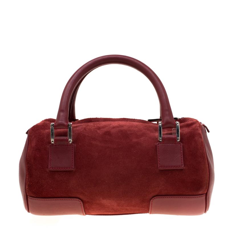 A spacious and stylish bag that can hold more than just your essentials with ease, this Loewe Amazona 36 satchel is a must-have for women on the go. Crafted in maroon suede, this bag is accented with red leather trims, two rolled top handles and
