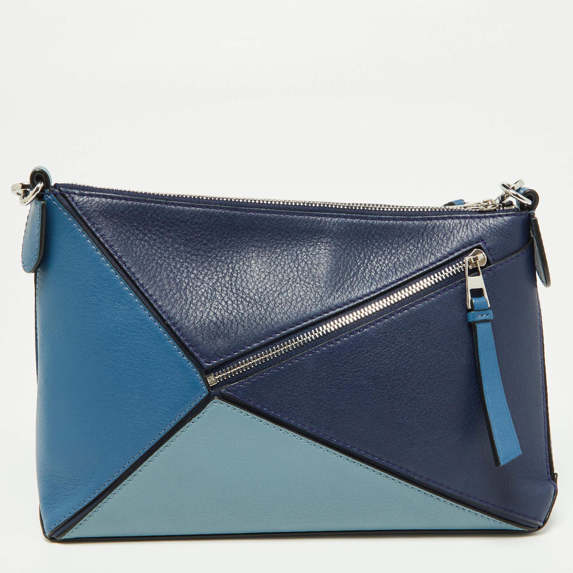 The Loewe Puzzle pochette bag is a stylish and compact accessory. Crafted from high-quality leather, it features a unique puzzle-like design in varying shades of blue. The bag is perfect for carrying essentials and exudes a modern and sophisticated