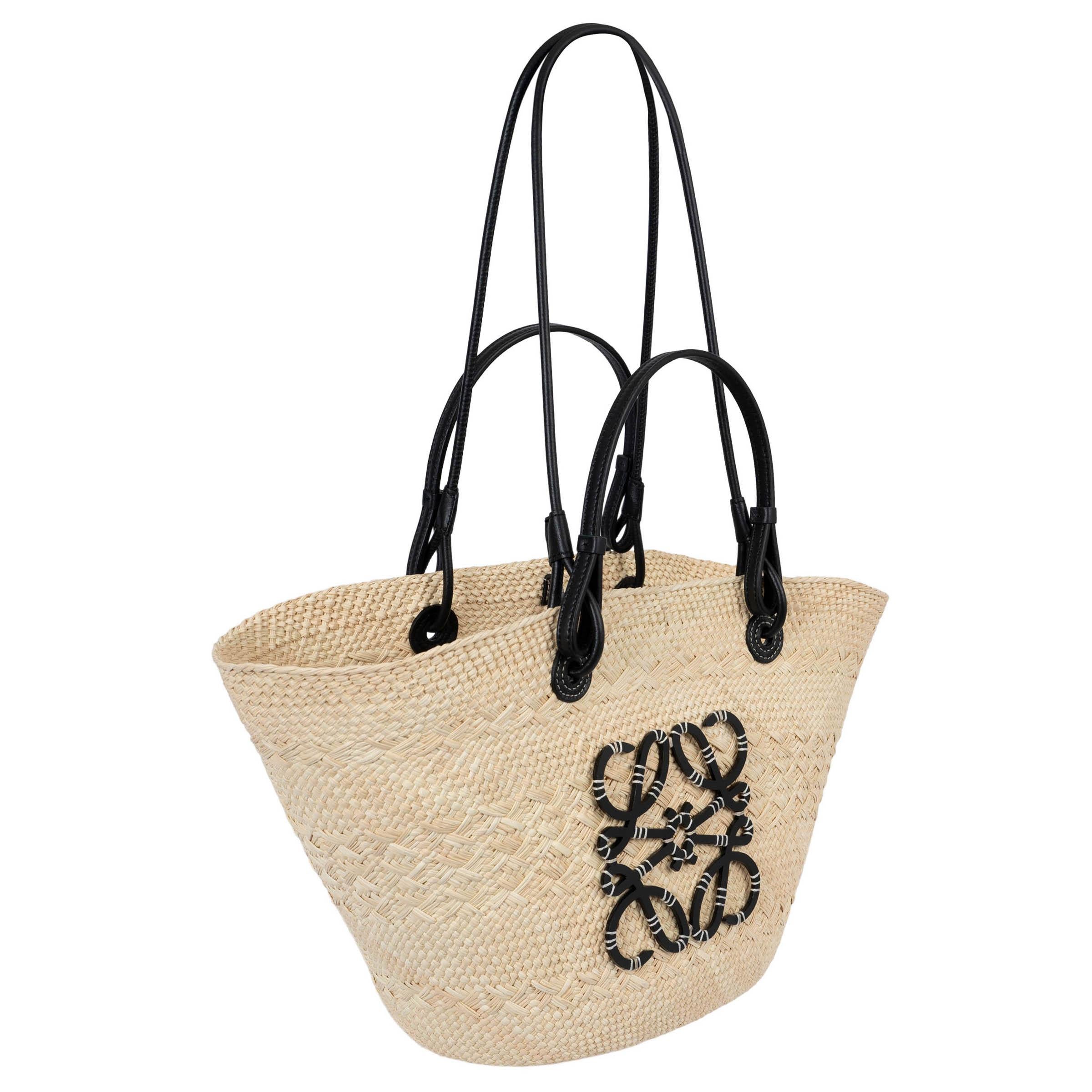 100% authentic Loewe Medium Anagram basket tote in handwoven iraca palm and black calfskin leather. Features black leather shoulder straps as well has top handles. Closes with self-tie leather straps on top. Unlined. Has been carried once or twice