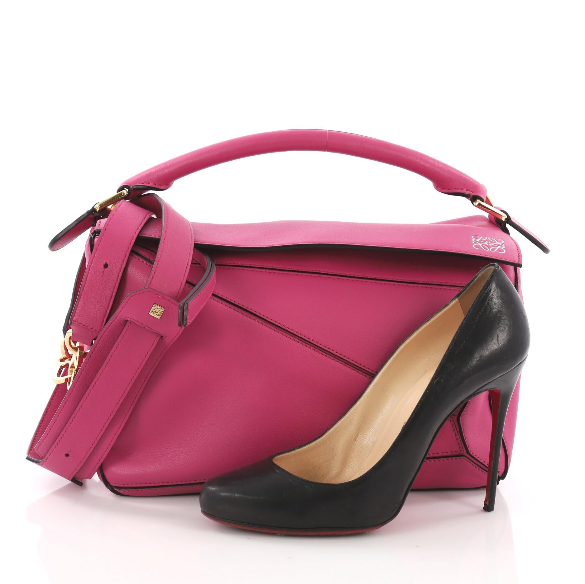 This Loewe Puzzle Bag Leather Medium, crafted in pink leather, features a top handle and gold-tone hardware. Its zip closure opens to a tan fabric interior with slip pockets. **Note: Shoe photographed is used as a sizing reference, and does not come