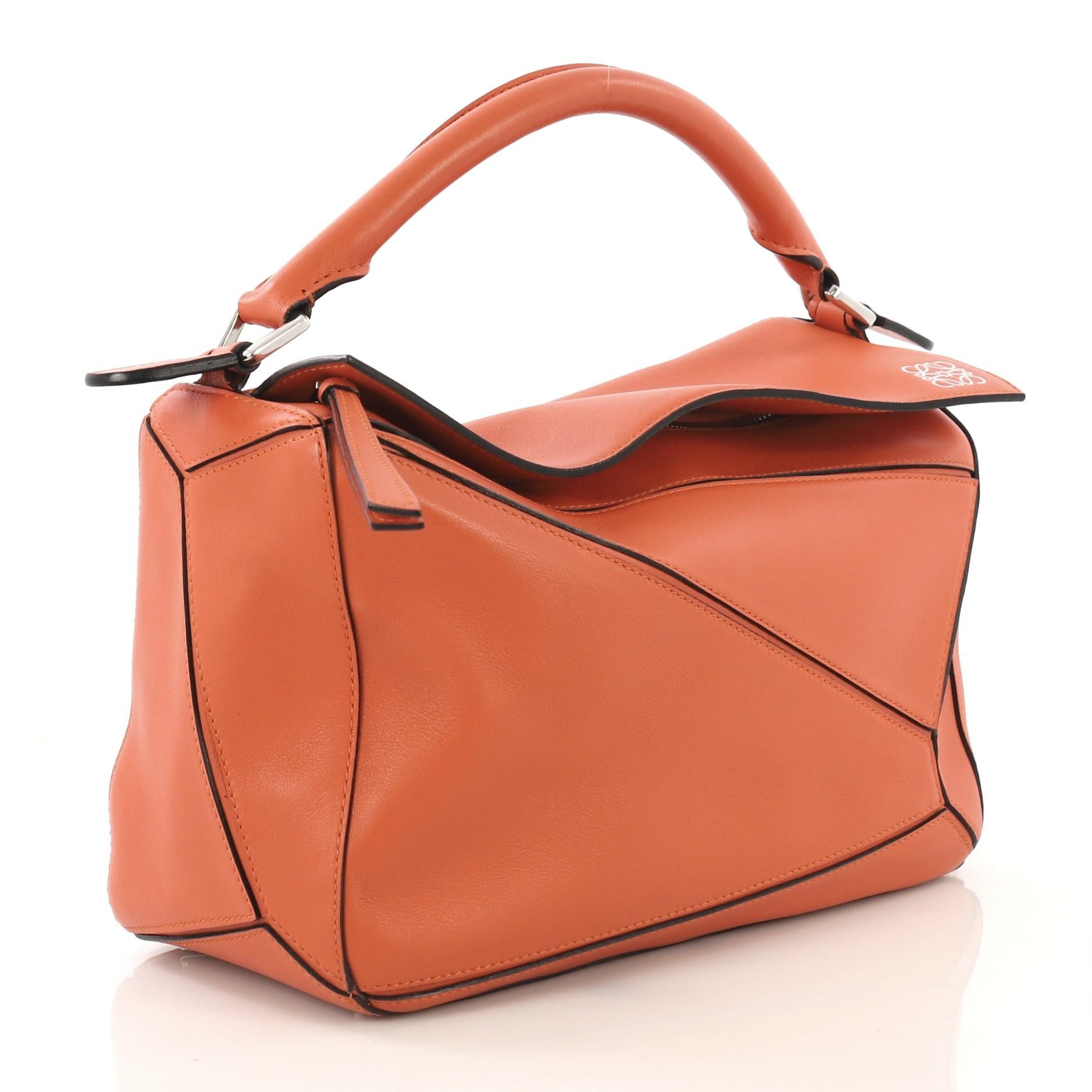 This Loewe Puzzle Bag Leather Medium, crafted in orange leather, features a leather top handle and silver-tone hardware. Its zip closure opens to a beige fabric interior with slip pockets. 

Estimated Retail Price: $2,450
Condition: Very good. Minor
