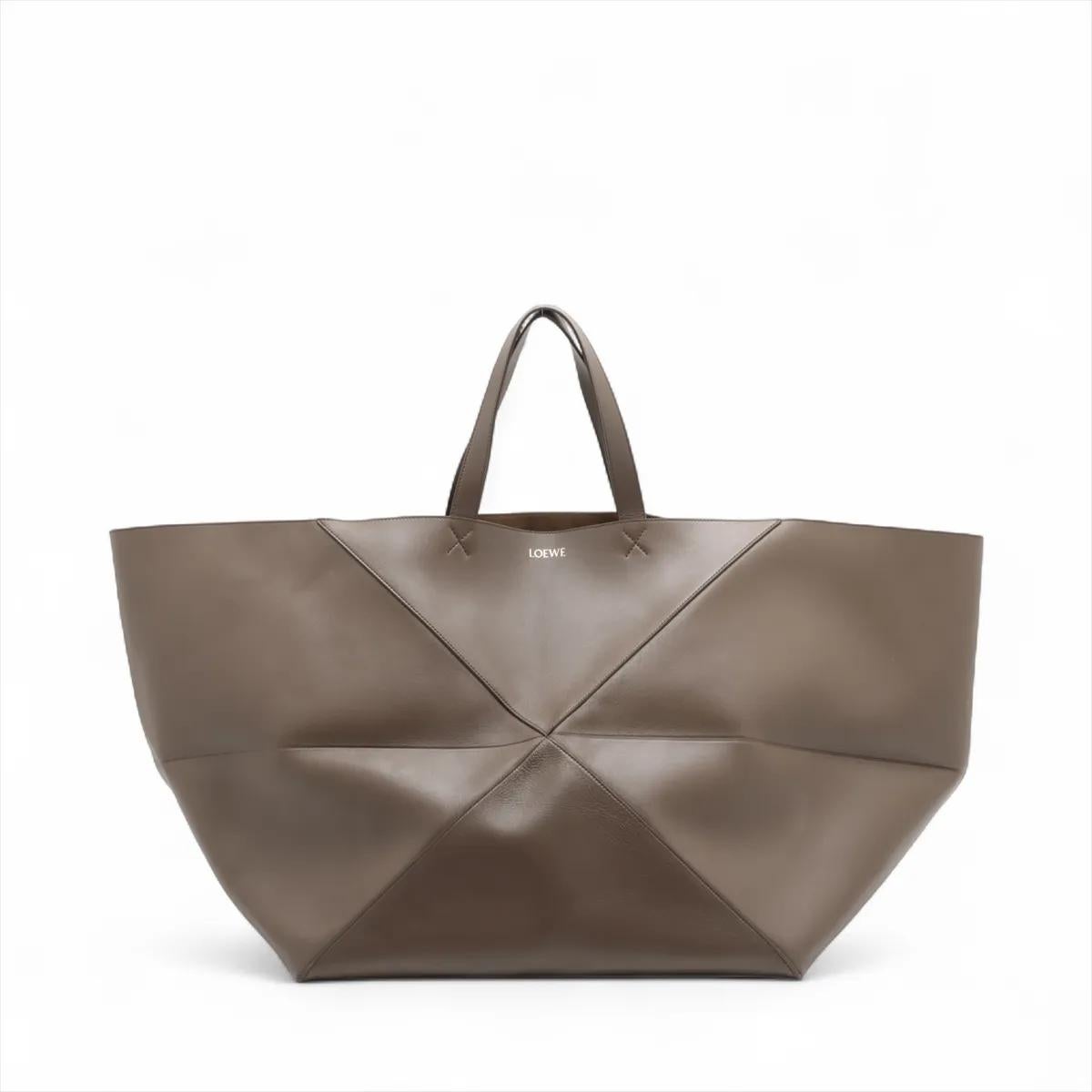 La borsa Loewe Puzzle Fold XXL in pelle marrone è un accessorio lussuoso e versatile, realizzato in morbida pelle con l'iconico design geometrico Puzzle del marchio. La sua silhouette oversize offre un fascino architettonico moderno, pur rimanendo