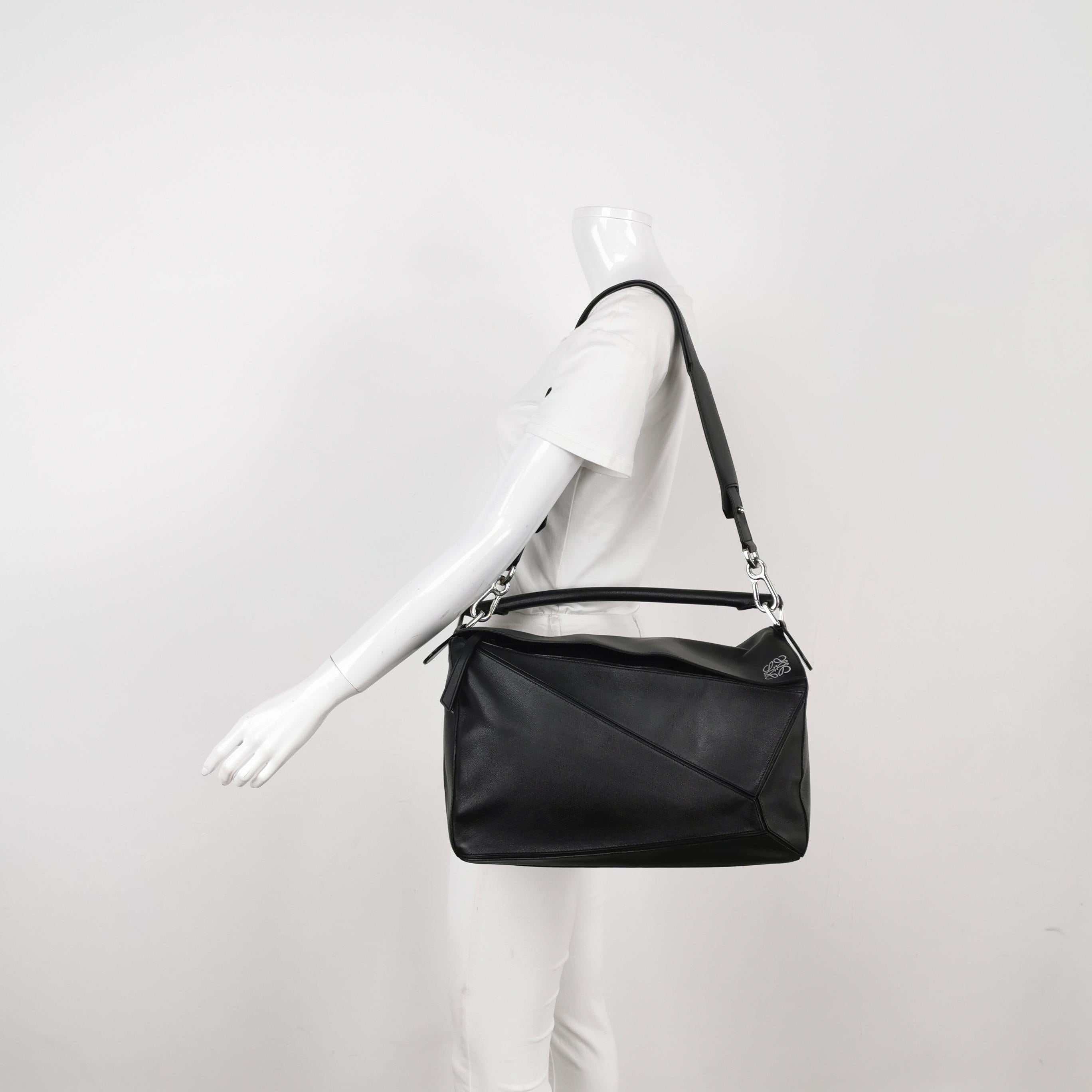 Loewe Puzzle Large Black Smooth Leather White Logo
These are professional photos of the actual bag offered by Luxbags.
Loewe's Puzzle bag is a timeless classic cult piece. Crafted from supple calfskin leather and finished with silver hardware and