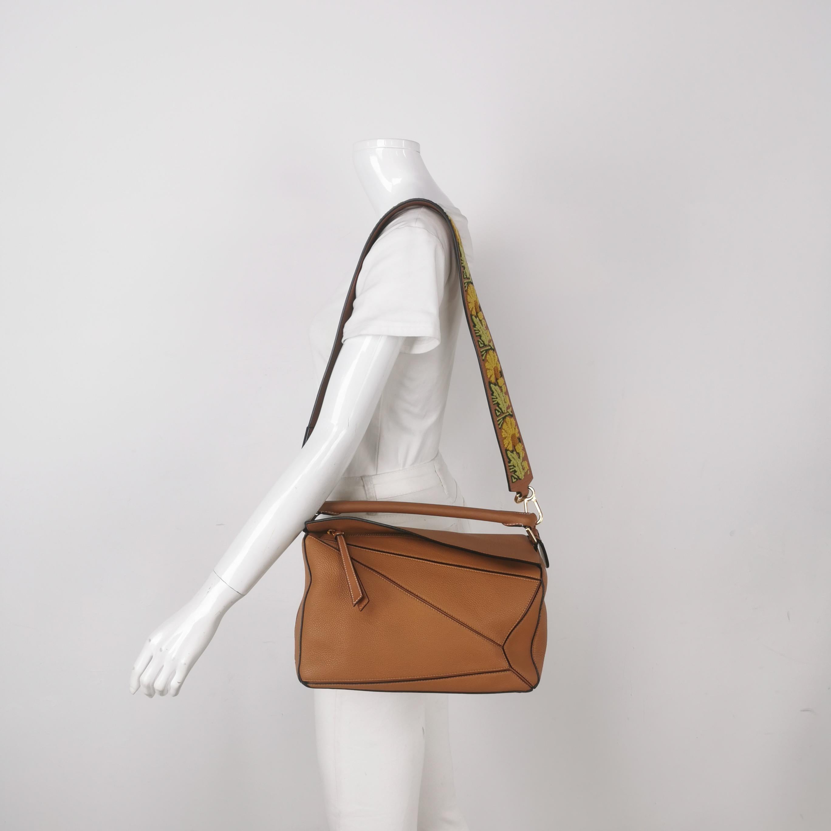 Loewe Puzzle Medium en cuir marron avec bracelet brodé multicolore
Il s'agit de photos professionnelles du sac offert par Luxbags.

Le sac Puzzle de Loewe est un classique intemporel et culte. Confectionné en cuir de veau souple, ce sac est