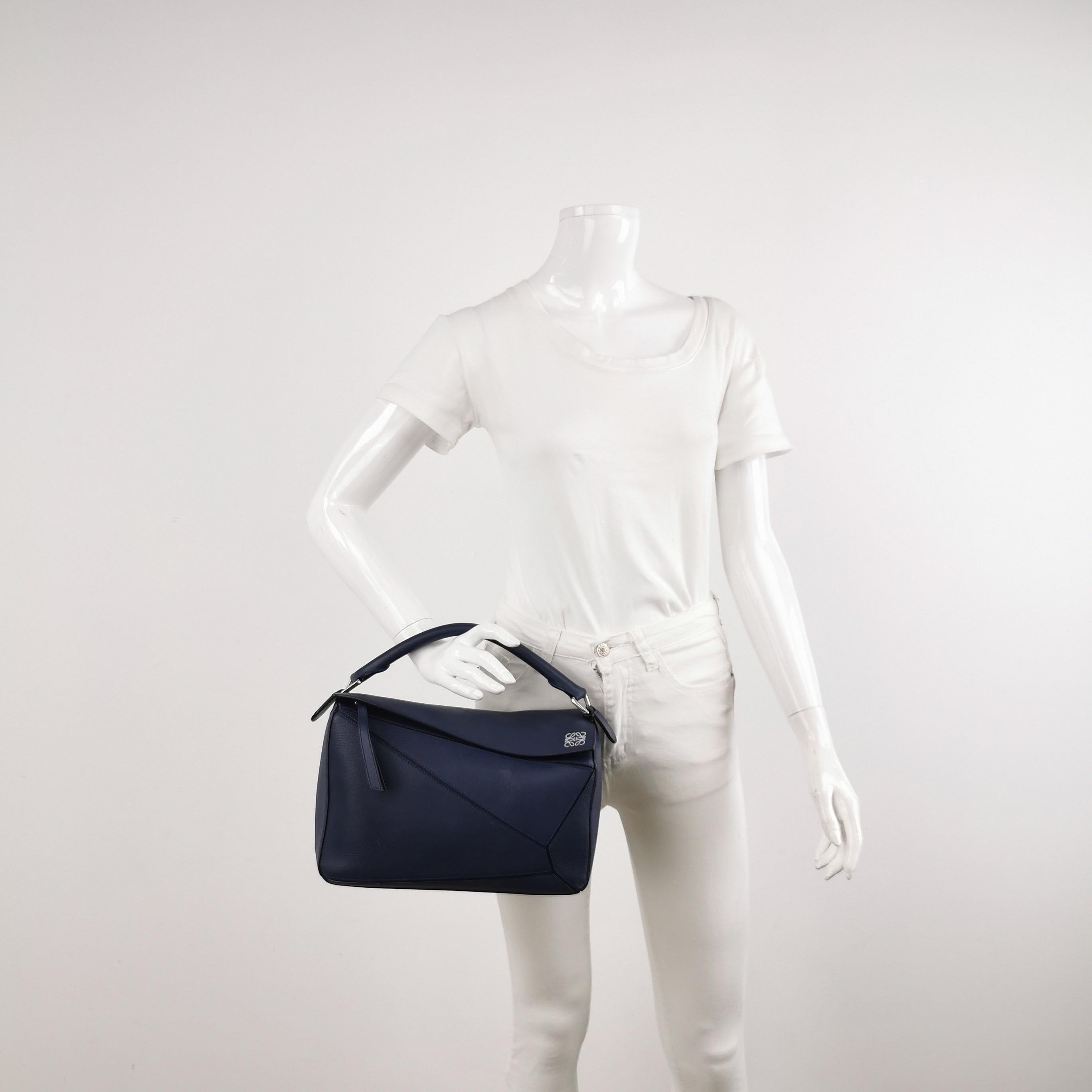 Loewe's Puzzle bag is a timeless classic cult piece. Crafted from supple calfskin leather and finished with silver hardware and signature origami-inspired panels, this bag is versatile and stylish. 

CONDITION: VERY GOOD 

This preloved item is in