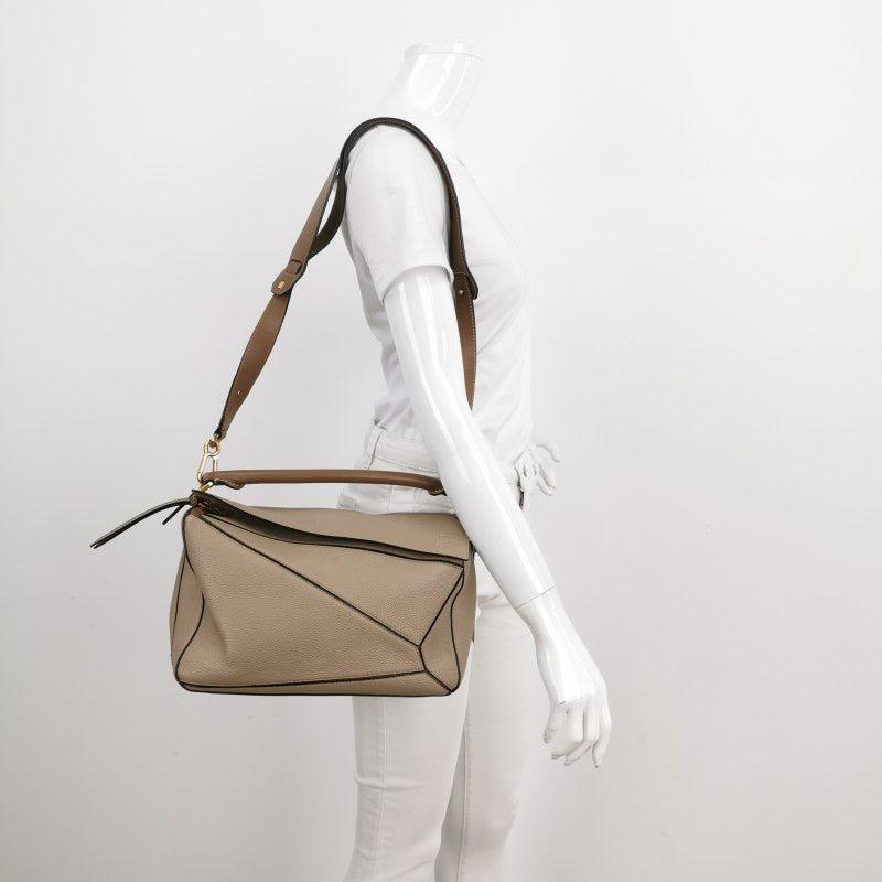 Loewe Puzzle Medium Sand Beige Calfskin Leather Bag Brown Strap
 These are professional photos of the actual bag.
 
 Loewe's Puzzle bag is a timeless classic cult piece. Crafted from supple calfskin leather and finished with silver hardware and