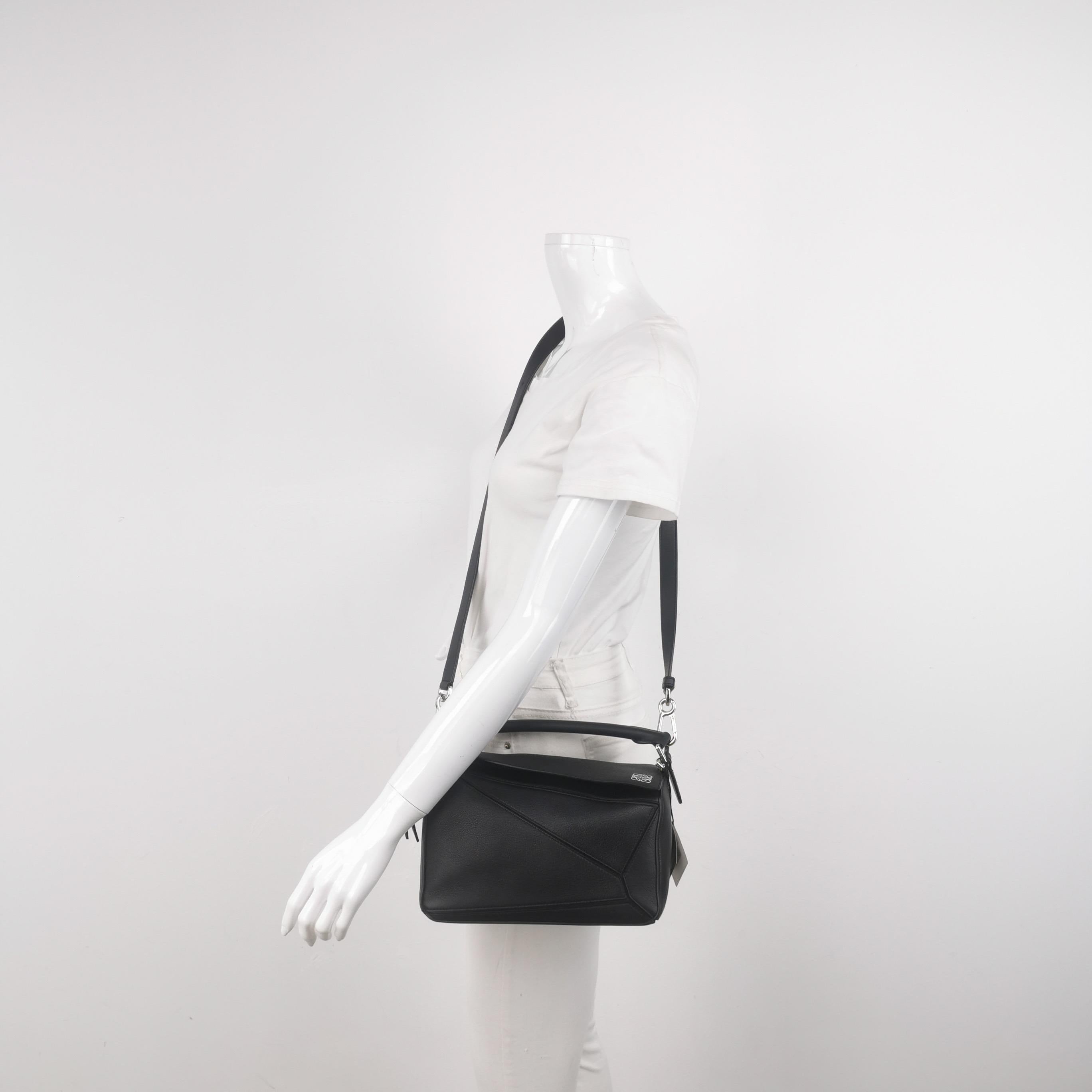 Loewe Puzzle Small Black Grained Leather White Logo
Il s'agit de photos professionnelles du sac offert par Luxbags.
Le sac Puzzle de Loewe est un classique intemporel et culte. Confectionné en cuir de veau souple, ce sac est polyvalent et élégant.