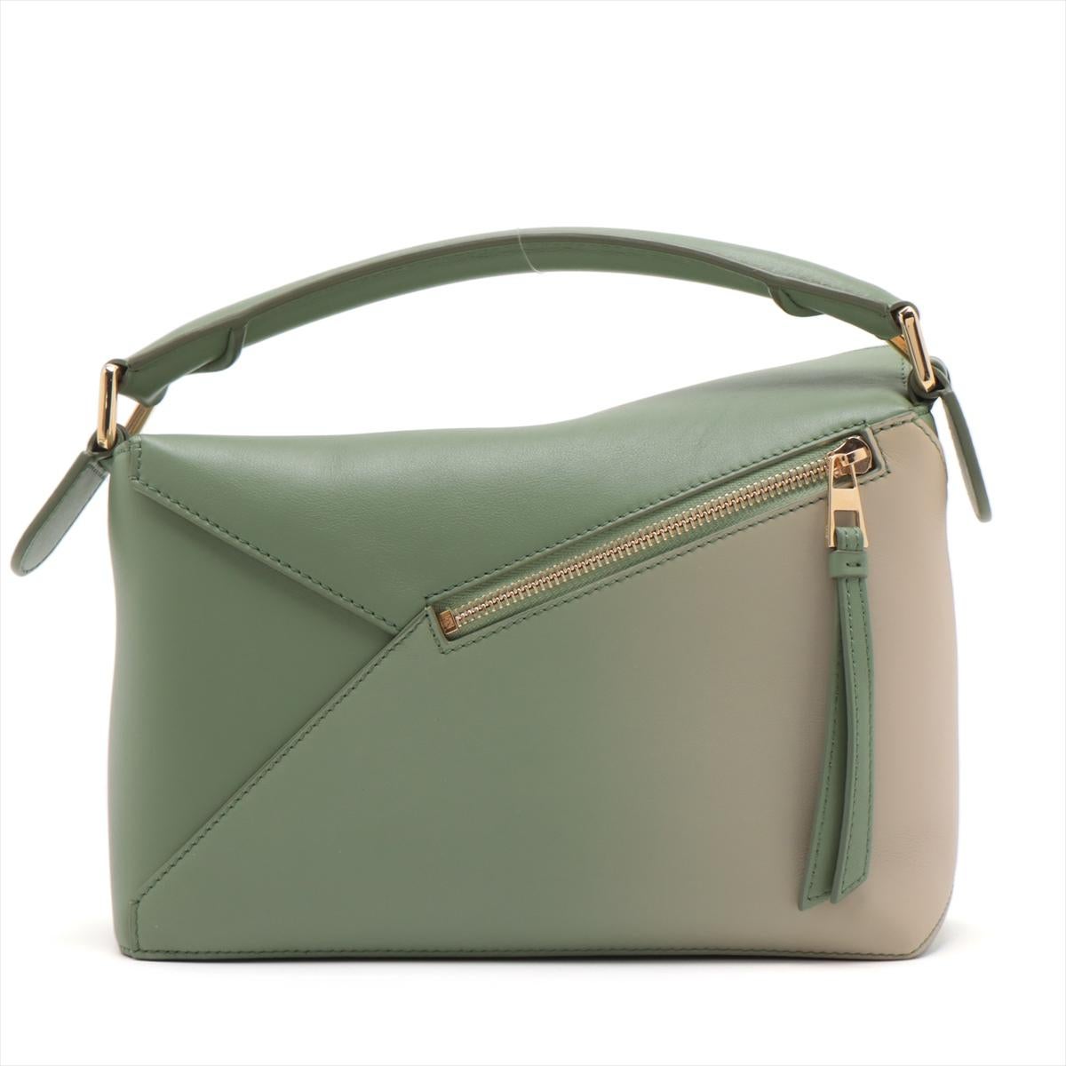 Die Loewe Puzzle Small Bag aus ruhigem, grünem, satiniertem Kalbsleder ist ein Beweis für die exquisite Handwerkskunst und das innovative Design von Loewe. Als Sinnbild für Vielseitigkeit lässt er sich mühelos auf drei verschiedene Arten stylen und