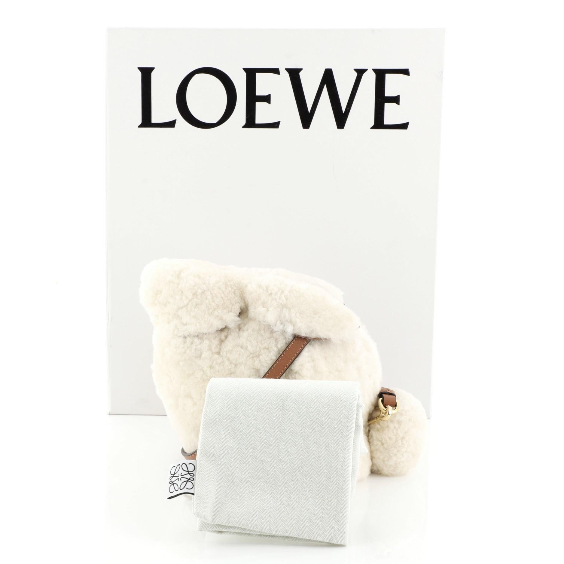 This Loewe Rabbit Crossbody Bag Shearling Mini, crafted from white shearling, features flat leather strap, leather trim, and gold-tone hardware. Its zip closure opens to a brown leather interior. 

Estimated Retail Price: $1,650
Condition:
