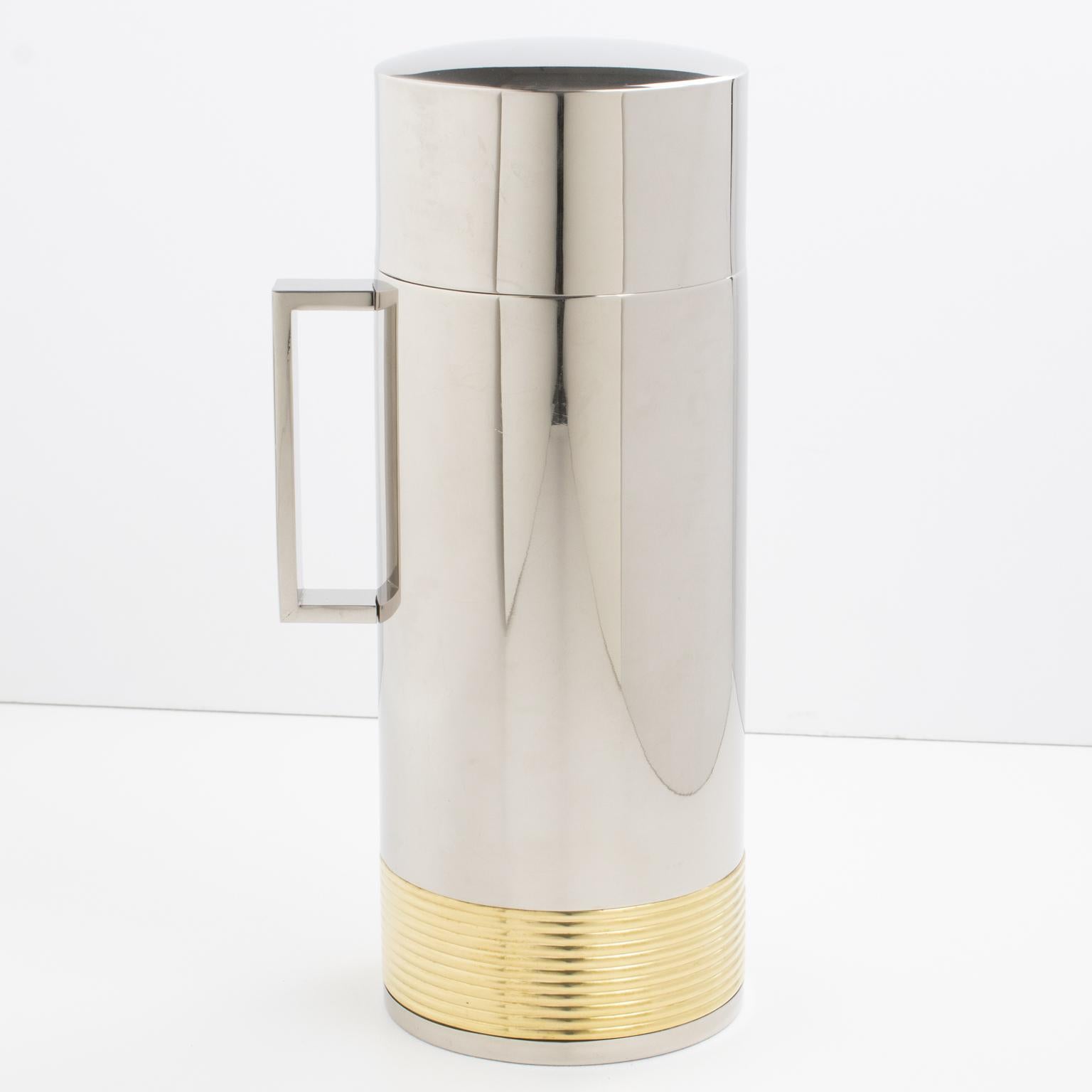 Ce thermos de bar élégant et moderniste est fabriqué en chrome et en laiton doré et a été produit par Loewe en Espagne, vers 1980. La carafe isotherme est dotée d'une large poignée plate et d'un design dimensionnel à rayures avec un décor de logo