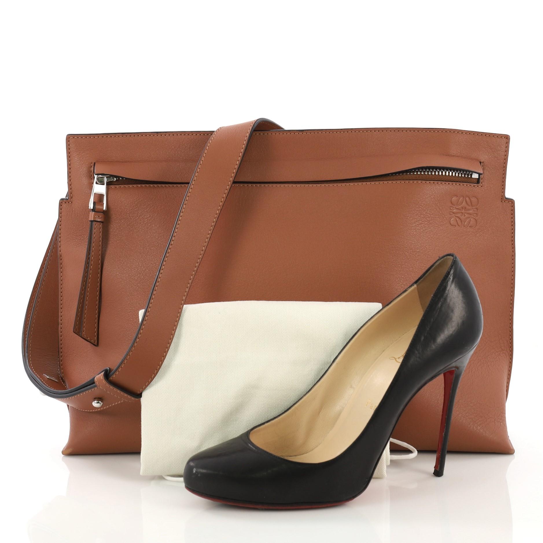 This Loewe T Messenger Leather Large, crafted in brown leather, features an adjustable shoulder strap, debossed designer anagram and silver-tone hardware. Its zip closure opens to a black fabric interior. **Note: Shoe photographed is used as a