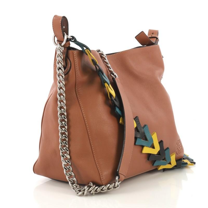 This Loewe V Bucket Bag Leather, crafted from brown leather, features a chain link strap, tricolor leather strap, and silver-tone hardware. Its magnetic closure opens to a beige fabric interior with snap pocket. 

Estimated Retail Price:
