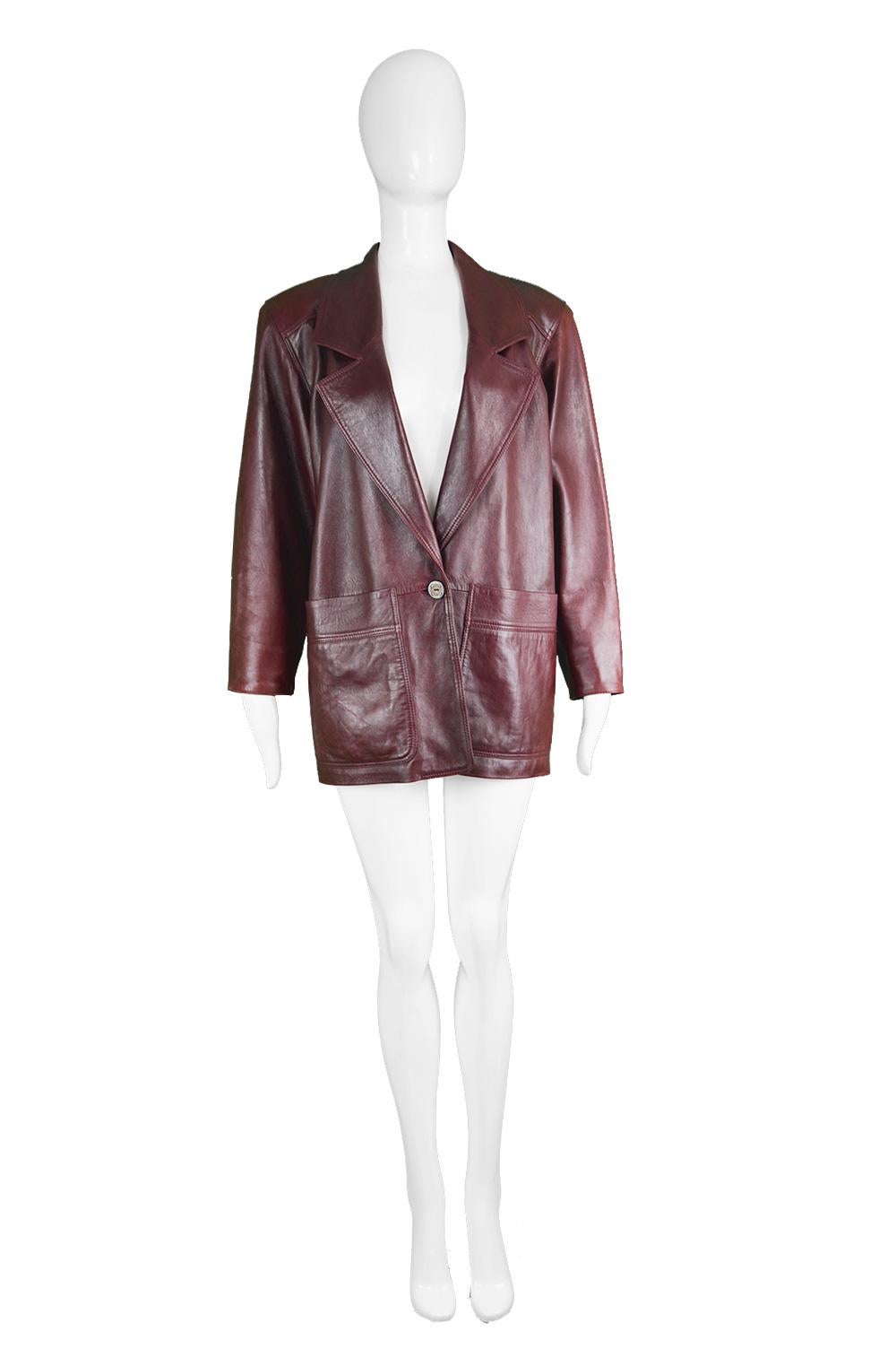 An edgy vintage women's leather jacket from the 80s by Spanish luxury fashion house, Loewe. In a dark red 'Bordeaux Wine' / oxblood leather with a single button engraved with the Loewe logo that fastens at the front. The structured shoulders give a
