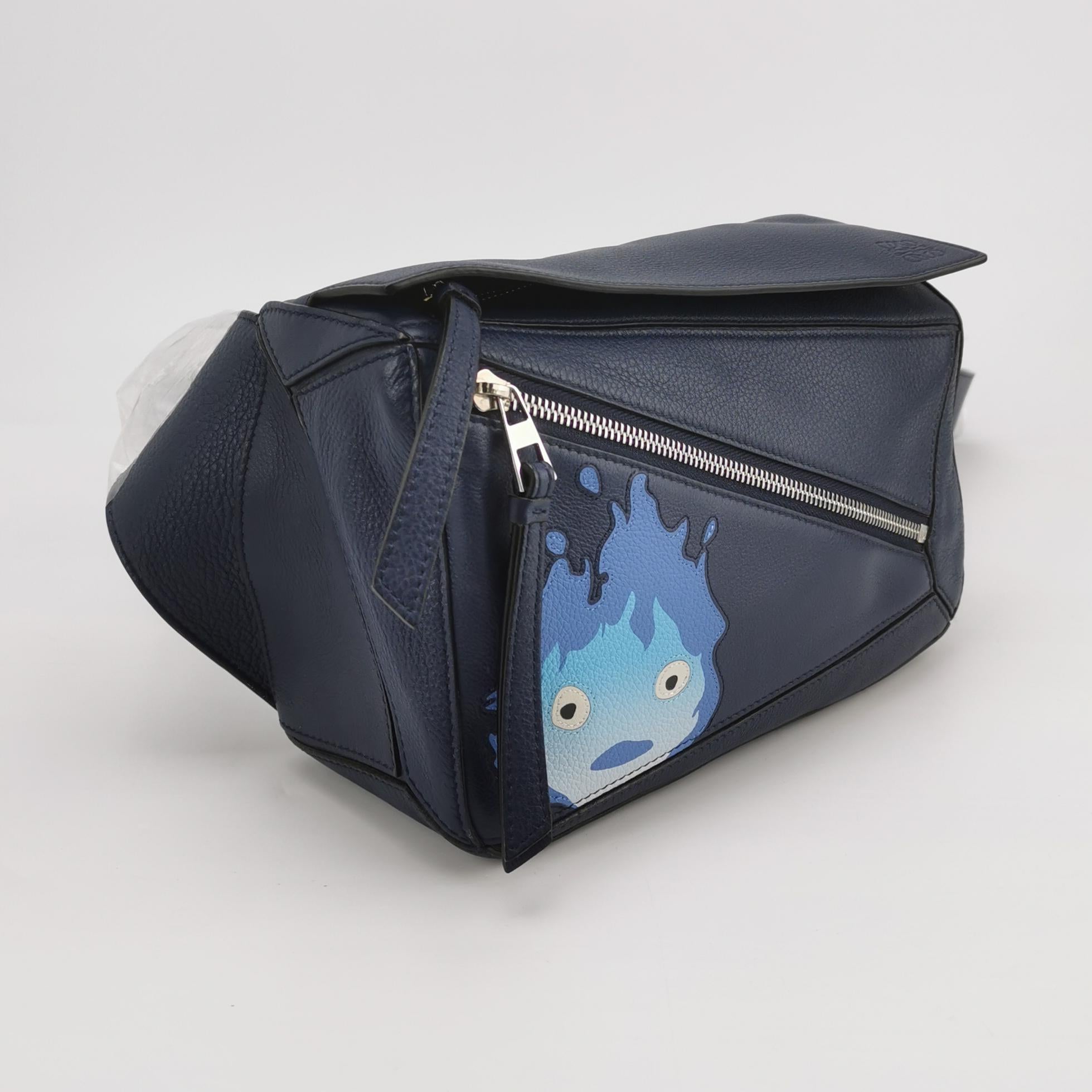 Riñonera Loewe x Howl's Moving Castle Studio Ghibli Calcifer Puzzle Pequeño Azul Marino
Estas son fotos profesionales de la bolsa real ofrecida por Luxbags.

Se trata de la colaboración entre Loewe y el estudio de anime japonés Studio Ghibli. Esta