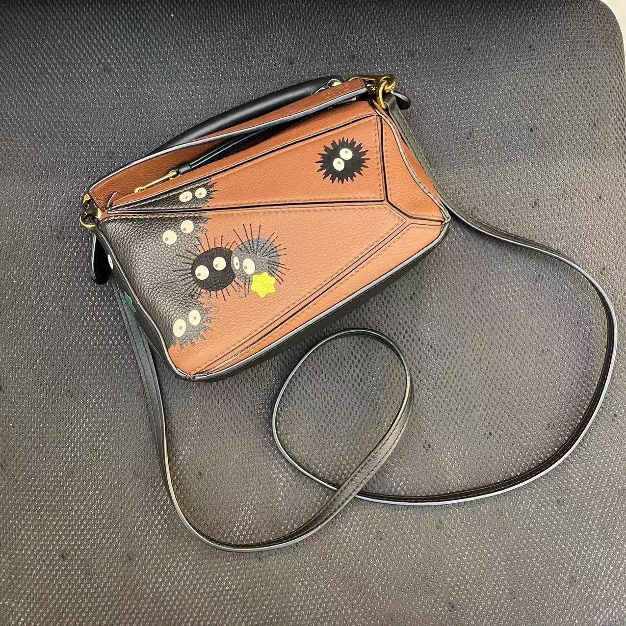 This is from the sell-out collaboration between Loewe and the Japanese anime studio Studio Ghibli. This particular mini puzzle bag features a character from the anime Spirited Away, the Susuwatari.

CONDITION: NEAR NEW

Light leather creases due to