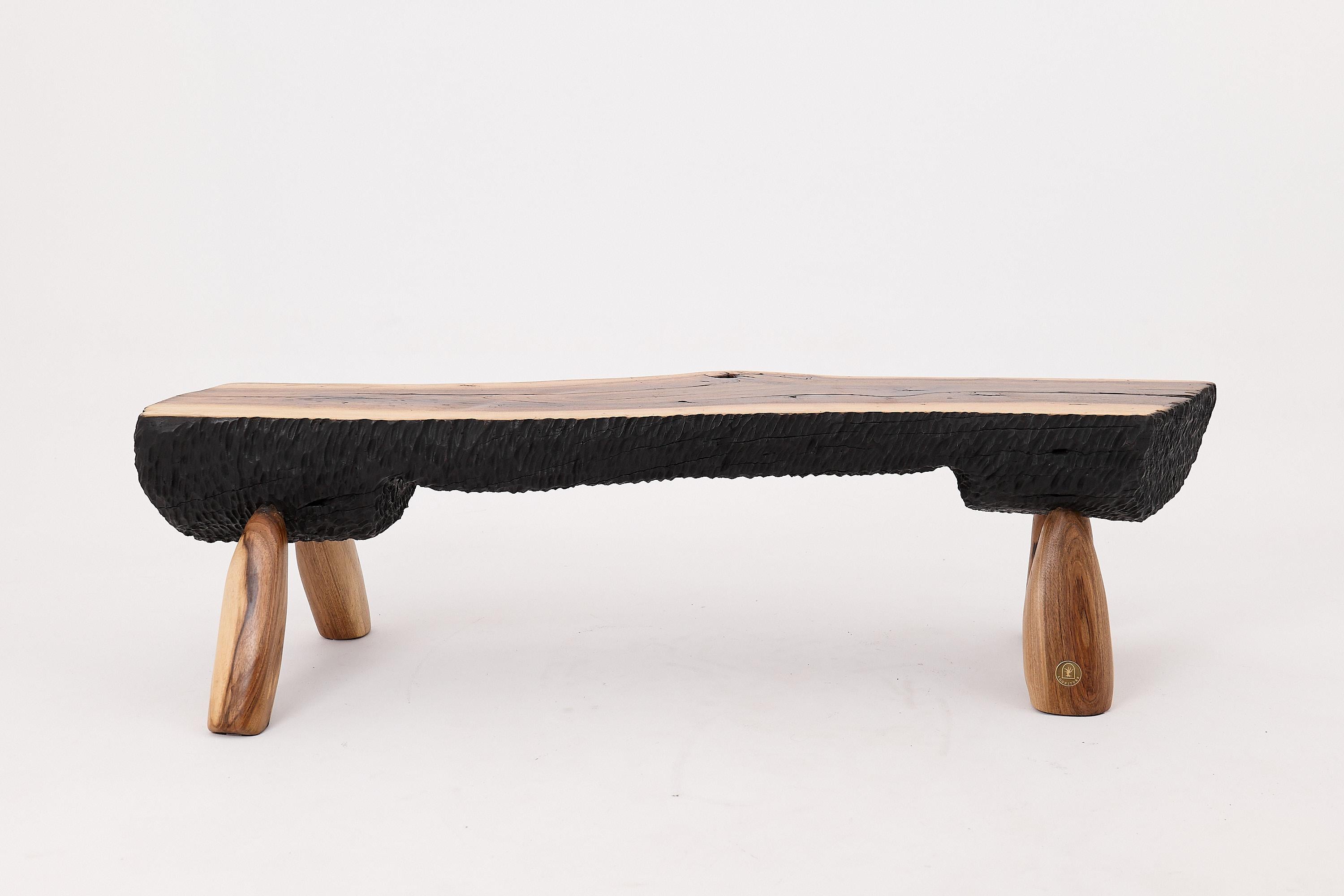 This sculptural bench is a one-of-a-kind work of functional art, handcrafted from a single solid hardwood slab and charred using the traditional shou sugi ban technique. Its long, organic profile follows the natural contours of the tree, preserving