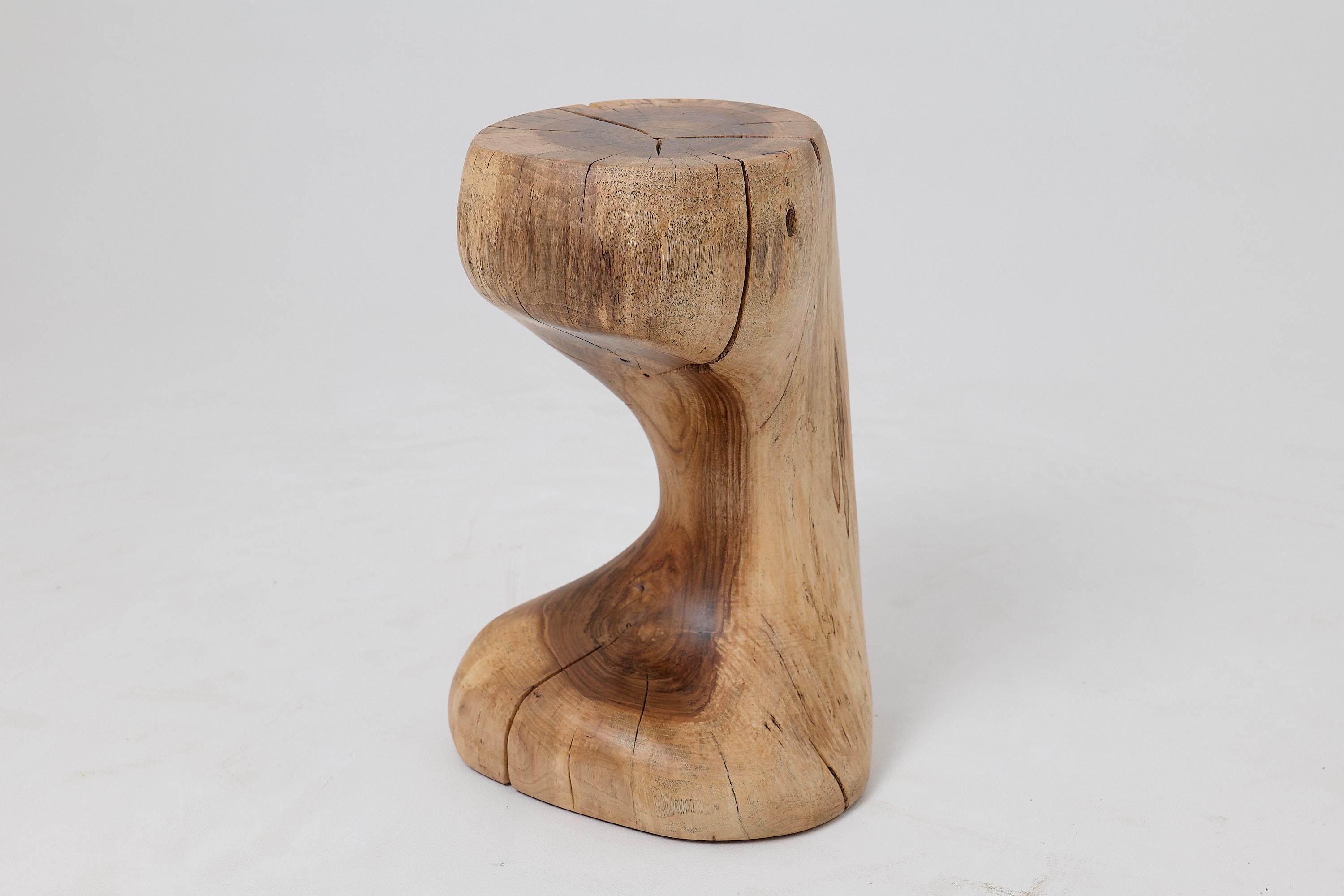 This biomorphic side table is a singular work of art, hand carved from a single hardwood log to achieve a perfect hourglass silhouette. Its form is a study in fluid curves and organic balance, creating a sense of graceful movement frozen in time.