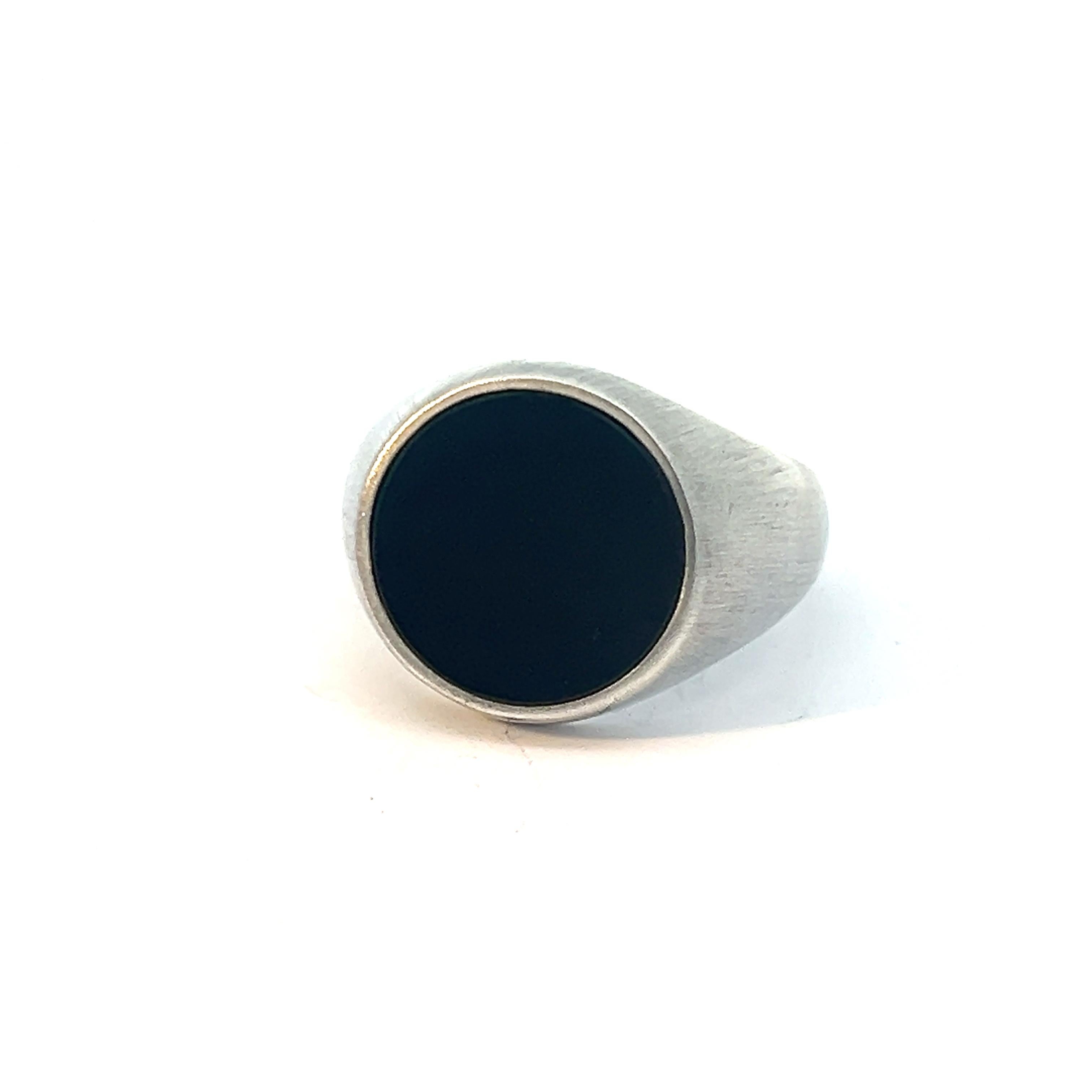 Meticulously crafted from sterling silver, this signet ring embodies understated sophistication and timeless appeal. Its classic design is elevated by a flat, round black onyx gemstone, exuding an air of refined elegance. The deep, lustrous hue of