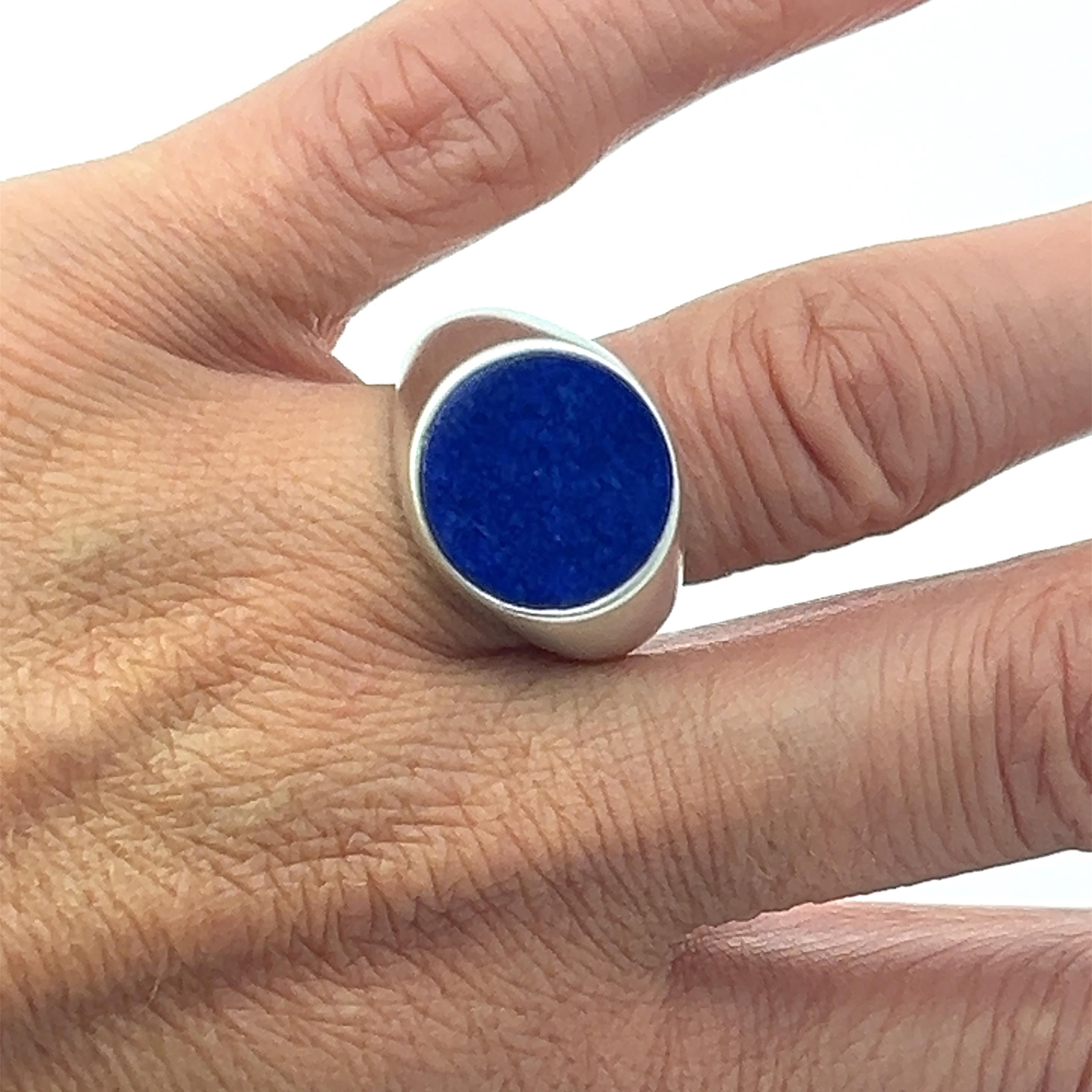 Introducing the Lois D. Sasson Design Sterling Silver Lapis Lazuli Signet Men's Ring. This sophisticated piece features a striking round lapis lazuli set at the center of a matte finish sterling silver band. The deep blue of the lapis lazuli