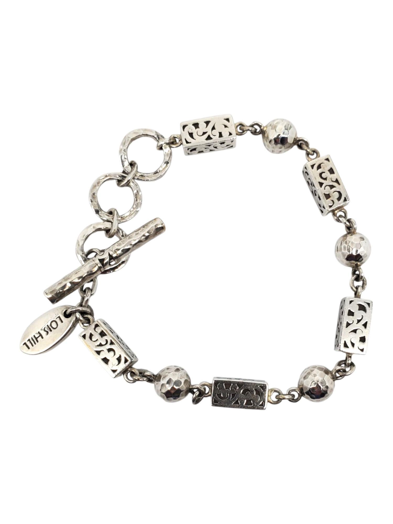 Lois Hill Sterling Silver Scroll & Bead Link Bracelet -

This elegant toggle bracelet by Lois Hill features hand carved scrollwork on sterling silver rectangular links accented with smooth beads.

Size: Fits from 6 1/4